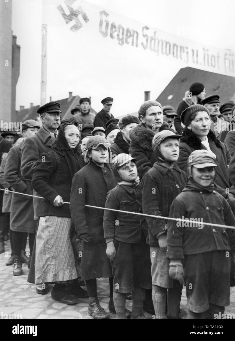 Foto di persone in ascolto di Reich il ministro della Propaganda Joseph Goebbels l' intervento in Gdansk presso la piazza del mercato in Neuteich. Al di sopra di un banner del NSDAP dicendo: "Contro il rosso e il nero". Foto Stock