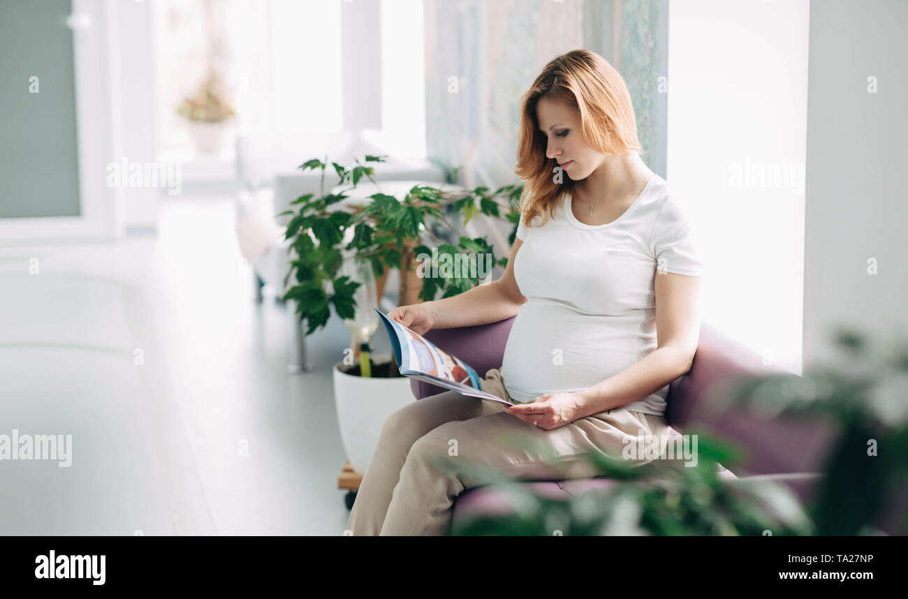 Donna incinta in attesa nel corridoio della clinica Foto Stock