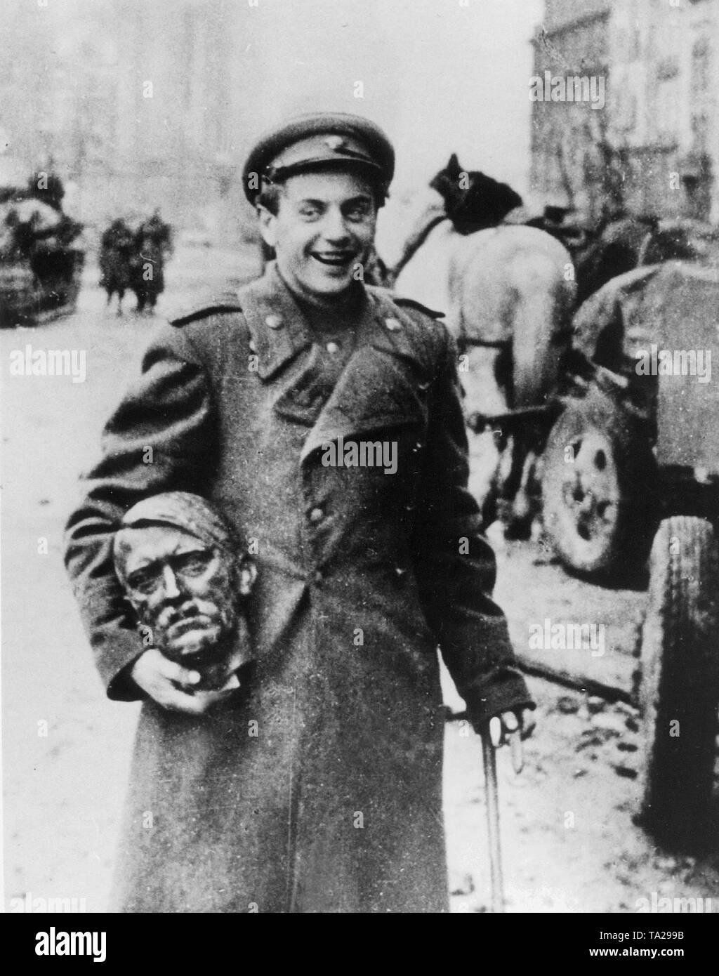 Un allegro ridere soldato sovietico porta un bronzo di Hitler testa come un souvenir, che egli ha trovato sotto le macerie delle distrutte Cancelleria del Reich immediatamente dopo la fine dei combattimenti. Foto Stock