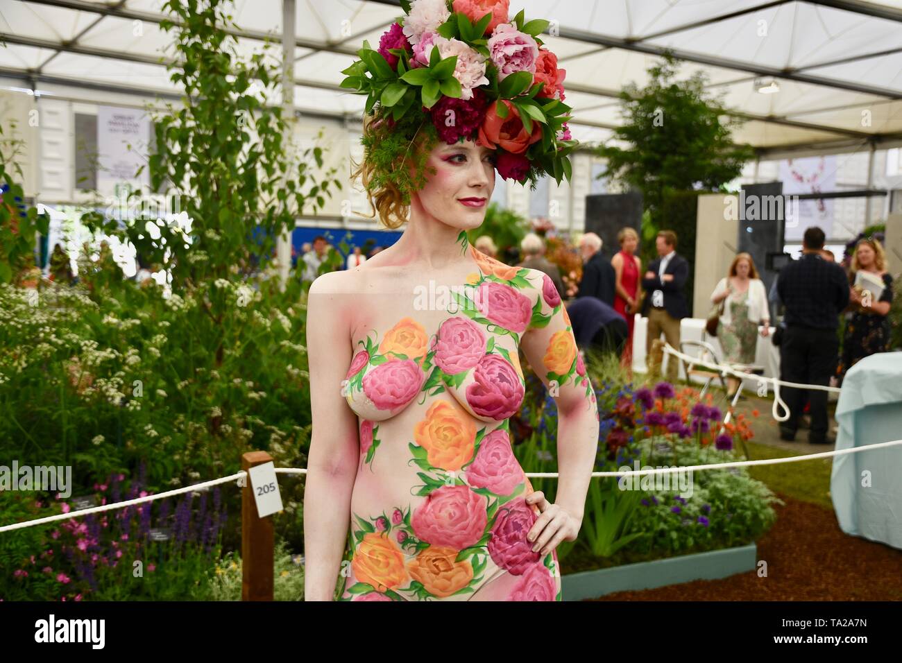 Un modello che indossa una ghirlanda di peonie e decorate con motivi floreali corpo art. RHS Chelsea Flower Show, premere giorno, Londra Foto Stock