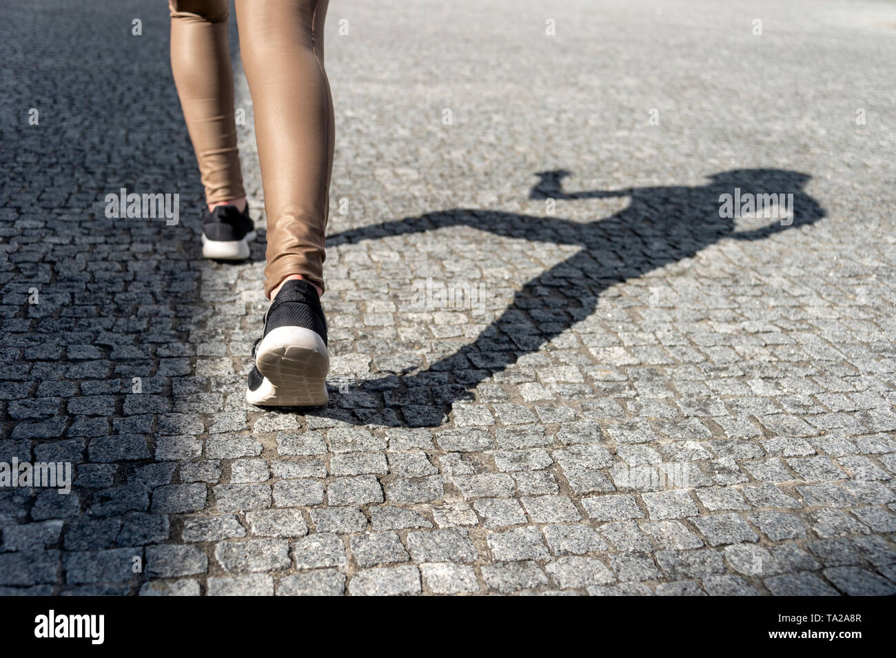 Close up di scarpe da donna in esecuzione con ombra sull'acciottolato Foto Stock