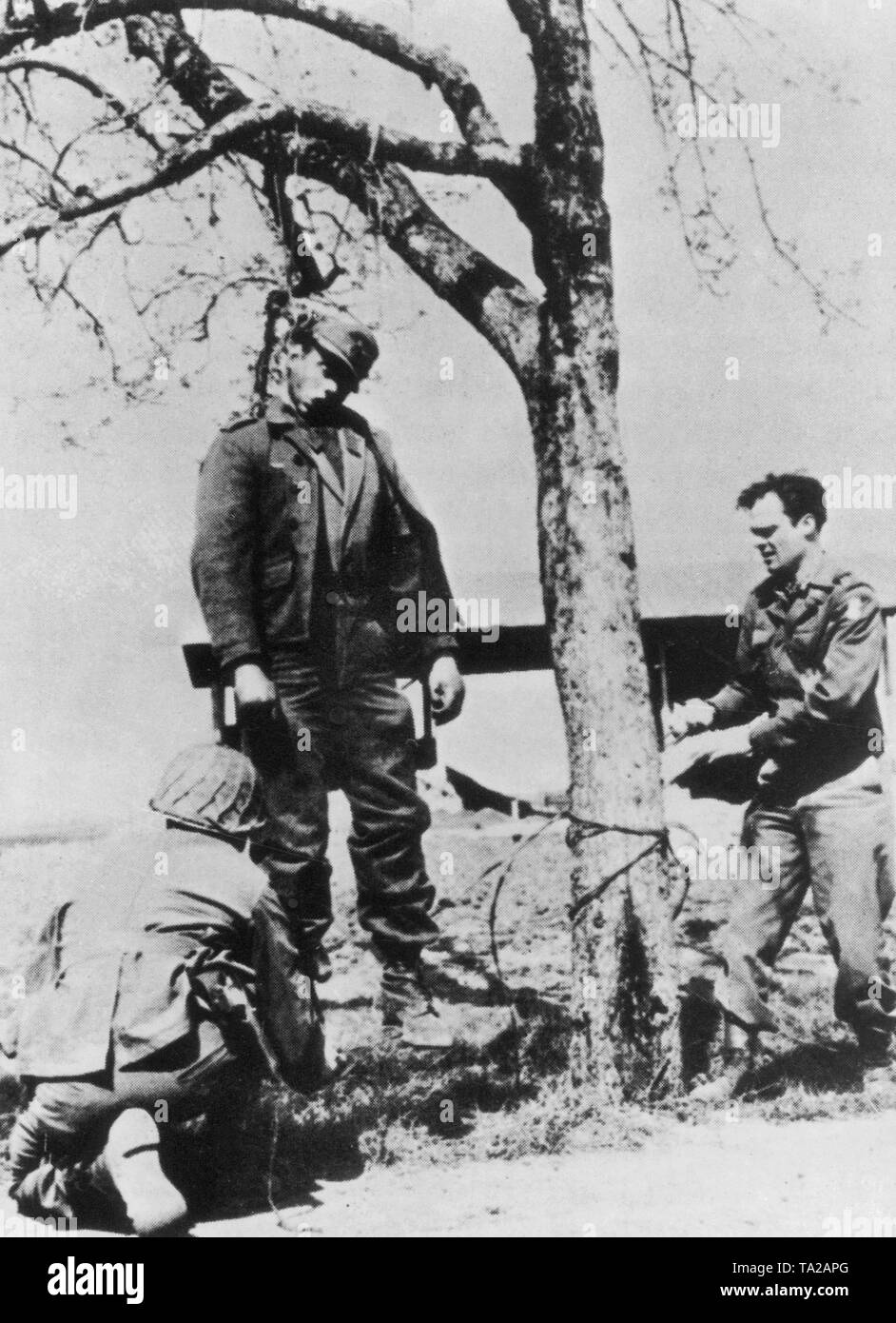 Soldati americani nella parte anteriore di un eseguito tedesco disertore. Un campo corte aveva condannato a morte e impiccato in pubblico come un deterrente. Foto Stock