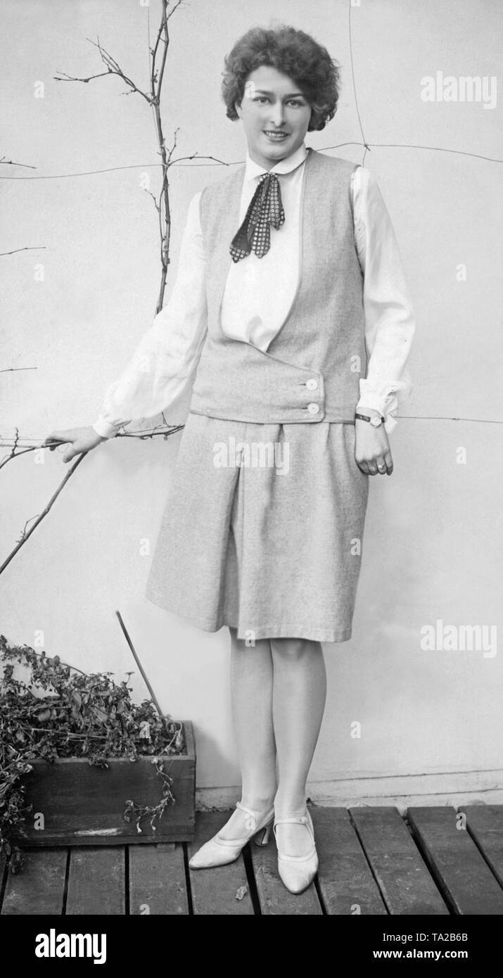 Una donna in posa di un mantello con abbinamento di giubbotto senza maniche e camicia bianca. Foto Stock