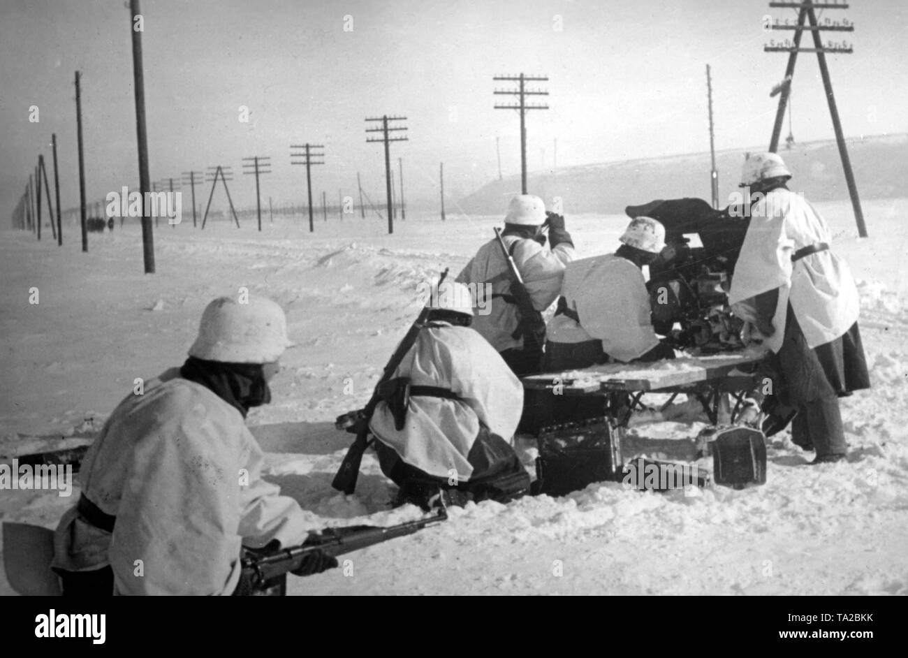 Soldati tedeschi sono il posizionamento di un Pak 3,7cm 35/36 anti-pistola serbatoio su una coperta di neve settore ovest di Mosca. I soldati ancora indossare la loro estate uniformi e mimetizzano con letto bianco copre e tovaglie. In background sono più soldati che marciano in fondo alla strada. (PK foto: corrispondente di guerra Langl). Foto Stock