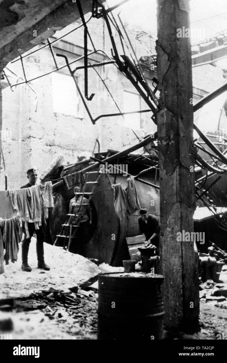 Soldati tedeschi nel loro bunker 'U-Boot' in una fabbrica distrutta vicino Volkhov. Essi utilizzano un distrutto a vapore impianto caldaia come base. Uno dei soldati si blocca servizio lavanderia su una linea. Foto di Propaganda Company (PK): corrispondente di guerra Wolkenstoerfer. Foto Stock