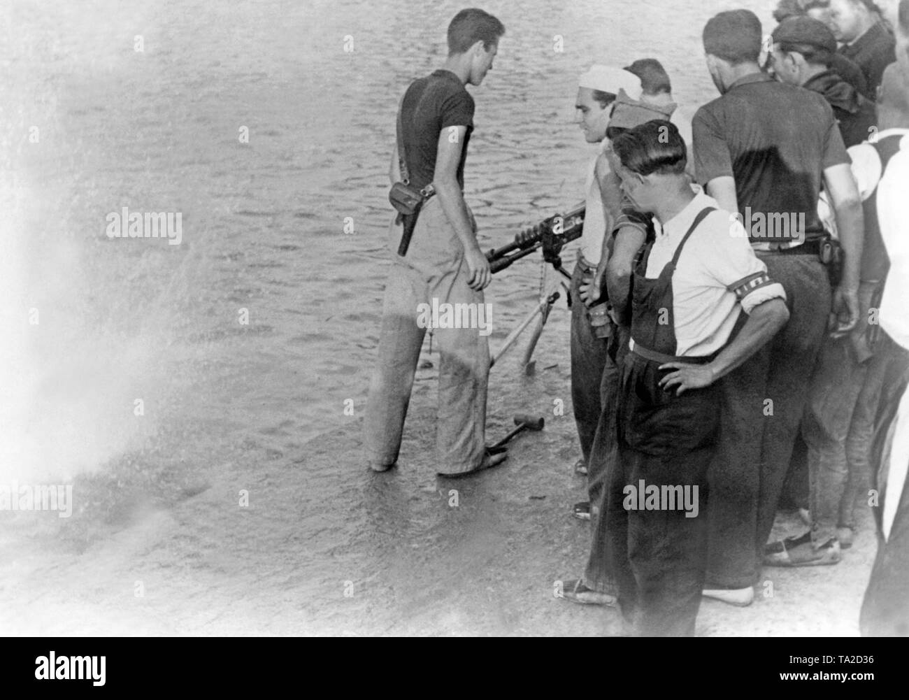 La guerra civile in Spagna, 1936 - battaglie in Isole Baleari. Foto di soldati repubblicani nel porto di Mahon, la capitale di Minorca, durante la battaglia delle Isole Baleari poco dopo lo scoppio della guerra civile in estate di 1936.i soldati sparano presso il muro del molo con un Hotchkiss M1914 mitragliatrice nell'acqua. Foto Stock
