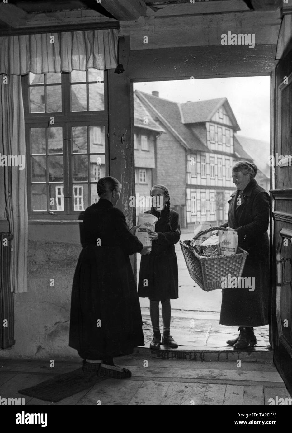 Un membro della NS-Frauenschaft ( socialista nazionale della Lega delle Donne) distribuisce 'Pfundspende" (beni donati) dell'inverno in rilievo a Goslar. Foto Stock