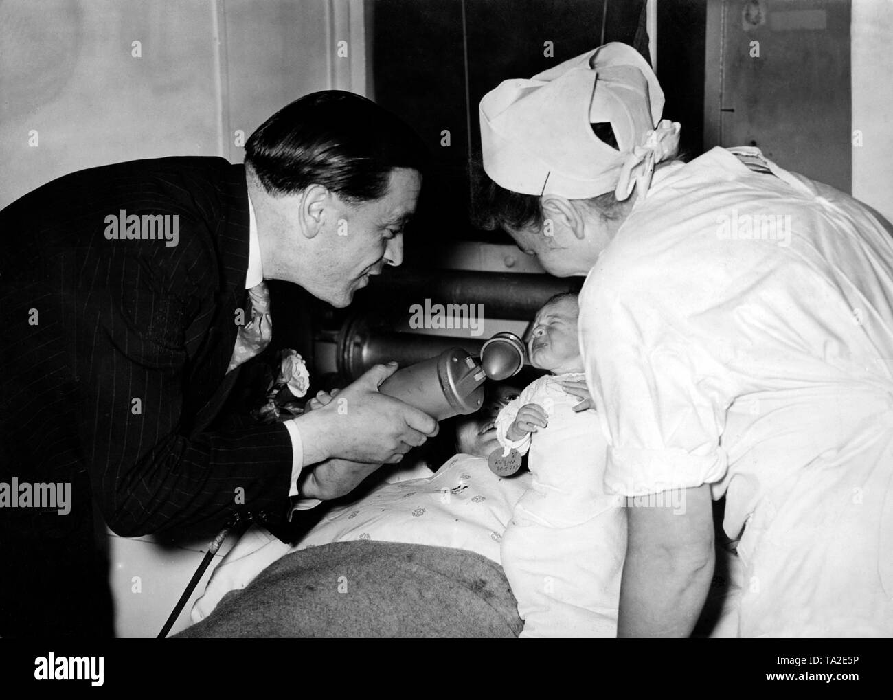 Emittente Rolf Wernecke si piega al di sopra del letto di un neonato in una Berlino ospedale di maternità con un microfono per inviare un messaggio di saluto "' per il padre del bambino sulla radio. La mattina del 1° luglio 1941, il cinquecentesimo programma della Kameradschaftsdienst è stato trasmesso, in cui i messaggi di saluto giornalieri sono stati trasmessi alla parte anteriore. In occasione del cinquecentesimo programma, a lunga distanza le cerimonie di nozze sono state trasmesse e le mamme sono stati visitati, che ha dato alla luce un bambino a notte. Foto Stock