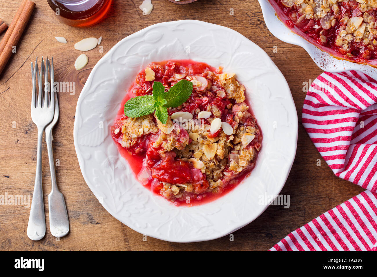 Sbriciolate con frutti di bosco in una piastra bianca. Vista dall'alto. Sfondo di legno. Foto Stock