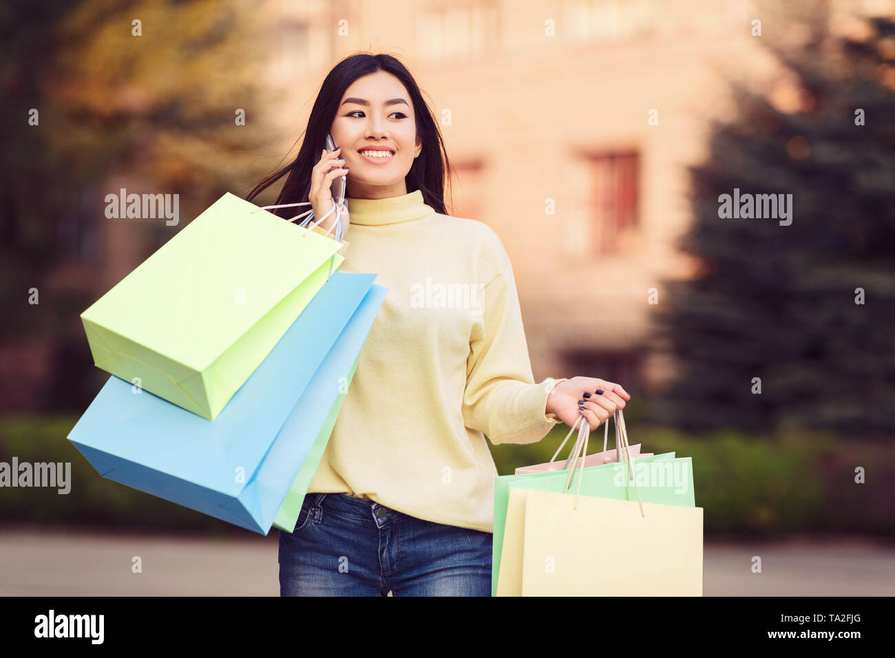 Felice Ragazza con Shopping Bags parlando al telefono Foto Stock