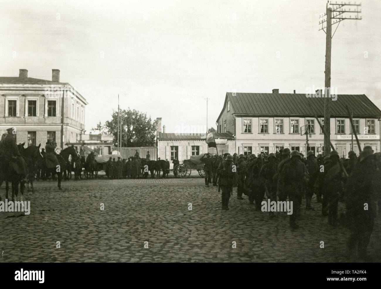Principali Josef Bischoff (2a sul suo cavallo, salutando) prende la salute delle sue truppe durante l invasione dei Freikorps " Ferro divisione" in Thorensberg, un quartiere di Riga. Sulla destra si trova un cartello con la scritta "Thorensberger Consum Verein'. Foto Stock