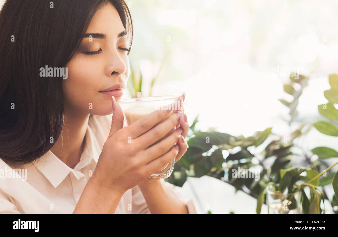 Attraente donna asiatica godendo l'odore del caffè del mattino Foto Stock
