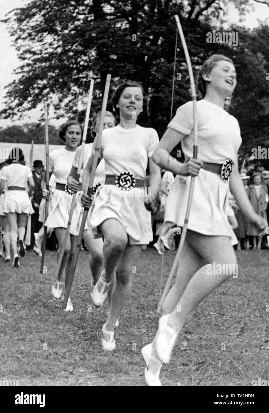 Durante la riunione dell'organizzazione nazista "Kraft durch Freude' ('Sforzo attraverso Gioia") di Amburgo, donne dal Gaugruppe Bochum eseguire esercizi sportivi con archi e frecce. L'emblema del lavoro tedesco anteriore viene visualizzato sulla propria cintura. Foto Stock