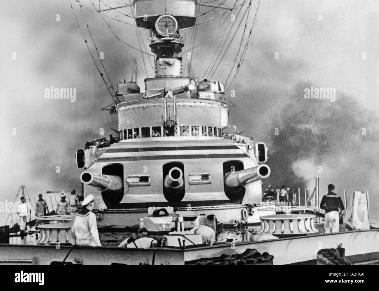 Il distrutto parzialmente incrociatore pesante Deutschland poco dopo il bombardamento da parte repubblicana due aerei da combattimento in maggio 1937 prima dell'isola delle Baleari. Accanto alla parte anteriore della torretta (tre 28cm Schnellfeuerkanone) aumento mazzette di fumo. Prima di esso, marinai sono impegnati nella lotta antincendio. Foto Stock