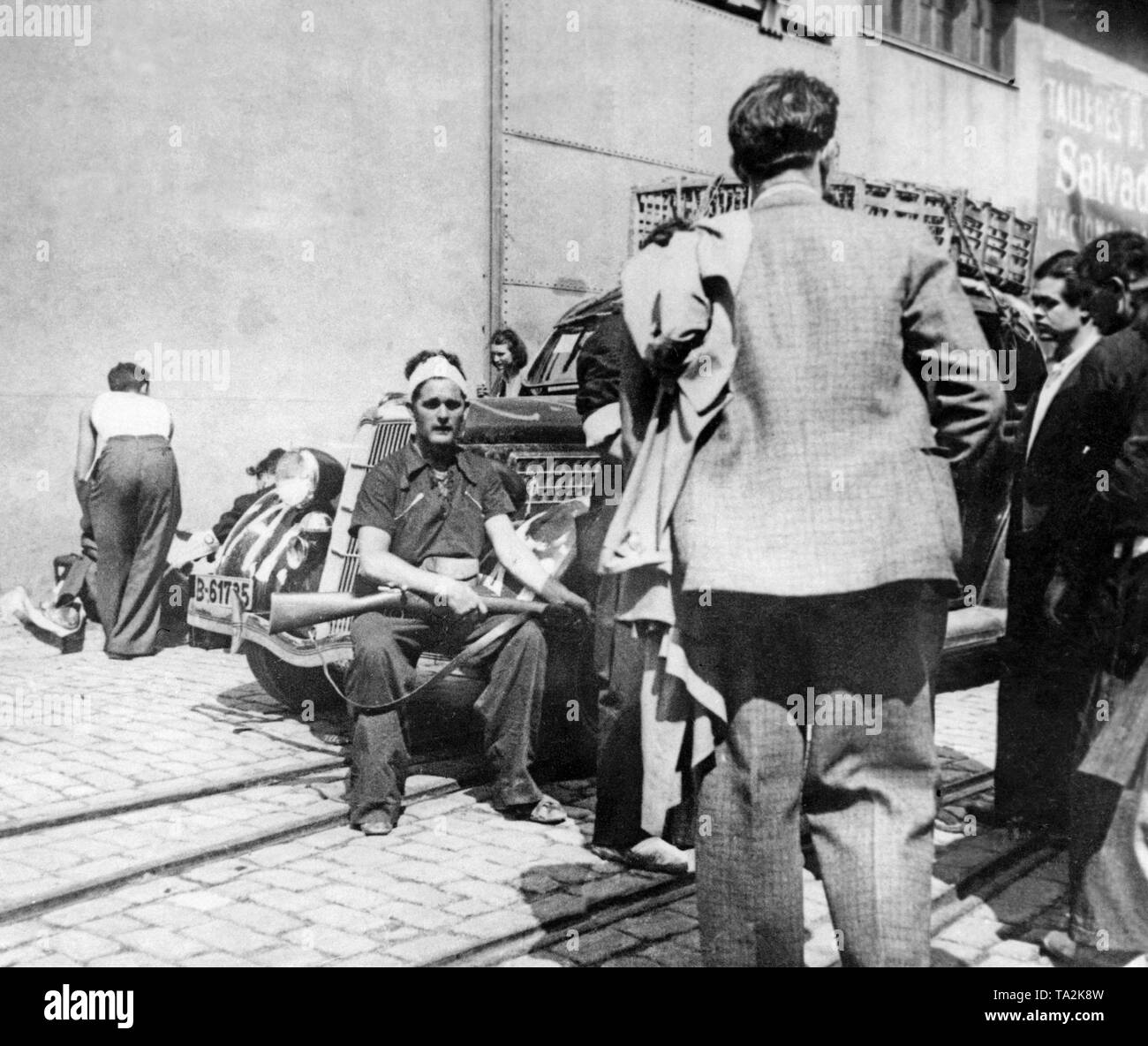 Foto di un gruppo di stranieri di combattenti volontari (sulla sinistra in  abiti civili) al loro arrivo presso la banchina del porto di Barcellona.  Dietro, un anarchico fighter seduta sul cofano di
