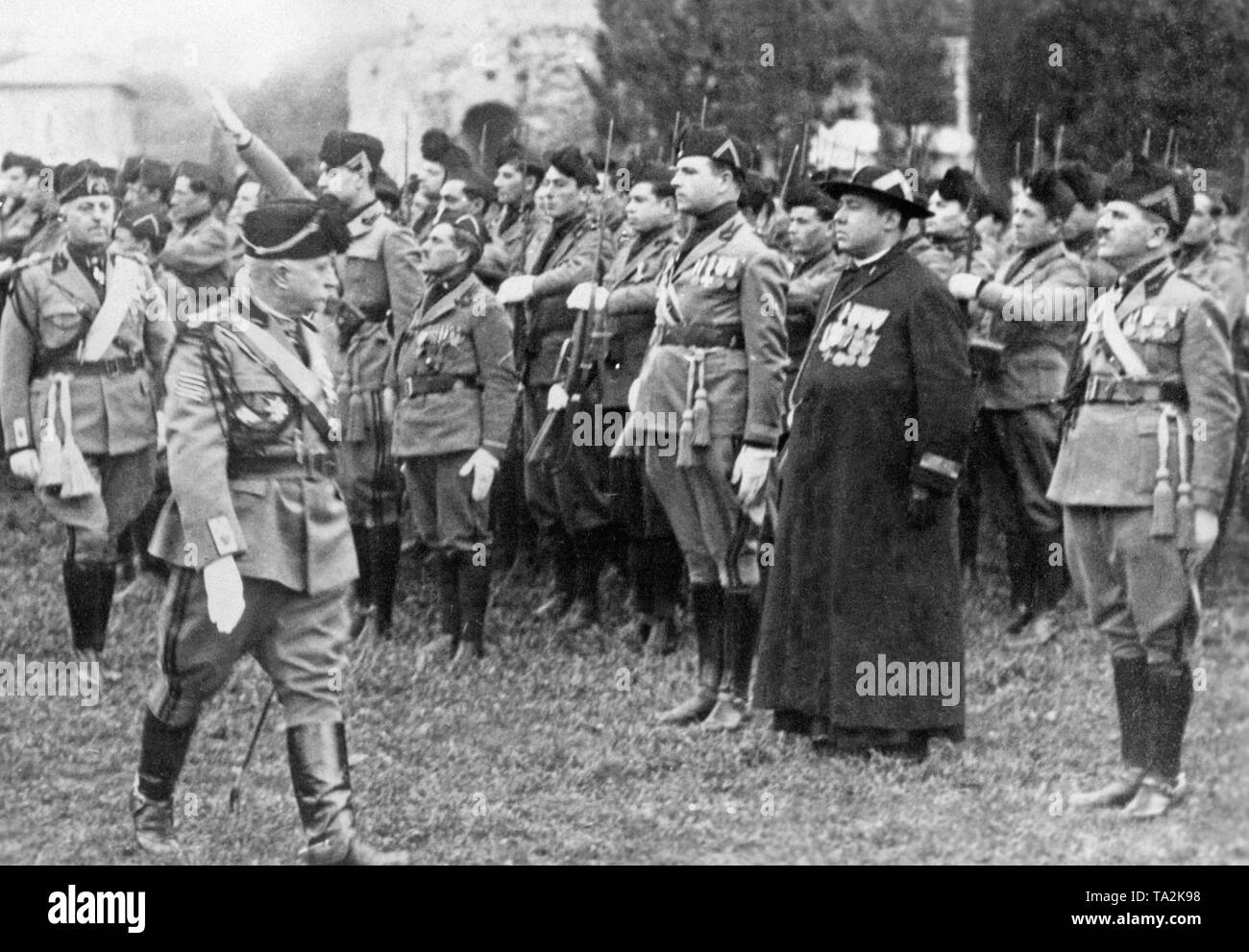 Un sacerdote decorate (secondo da destra) prende parte alla parata italiano della milizia fascista. Foto non datata. La riconciliazione dello stato italiano e il Vaticano è culminato nella conclusione dei Patti Lateranensi nel 1929. Foto Stock