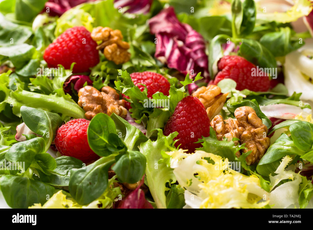 Una sana insalata verde con lampone e noci. Foto Stock