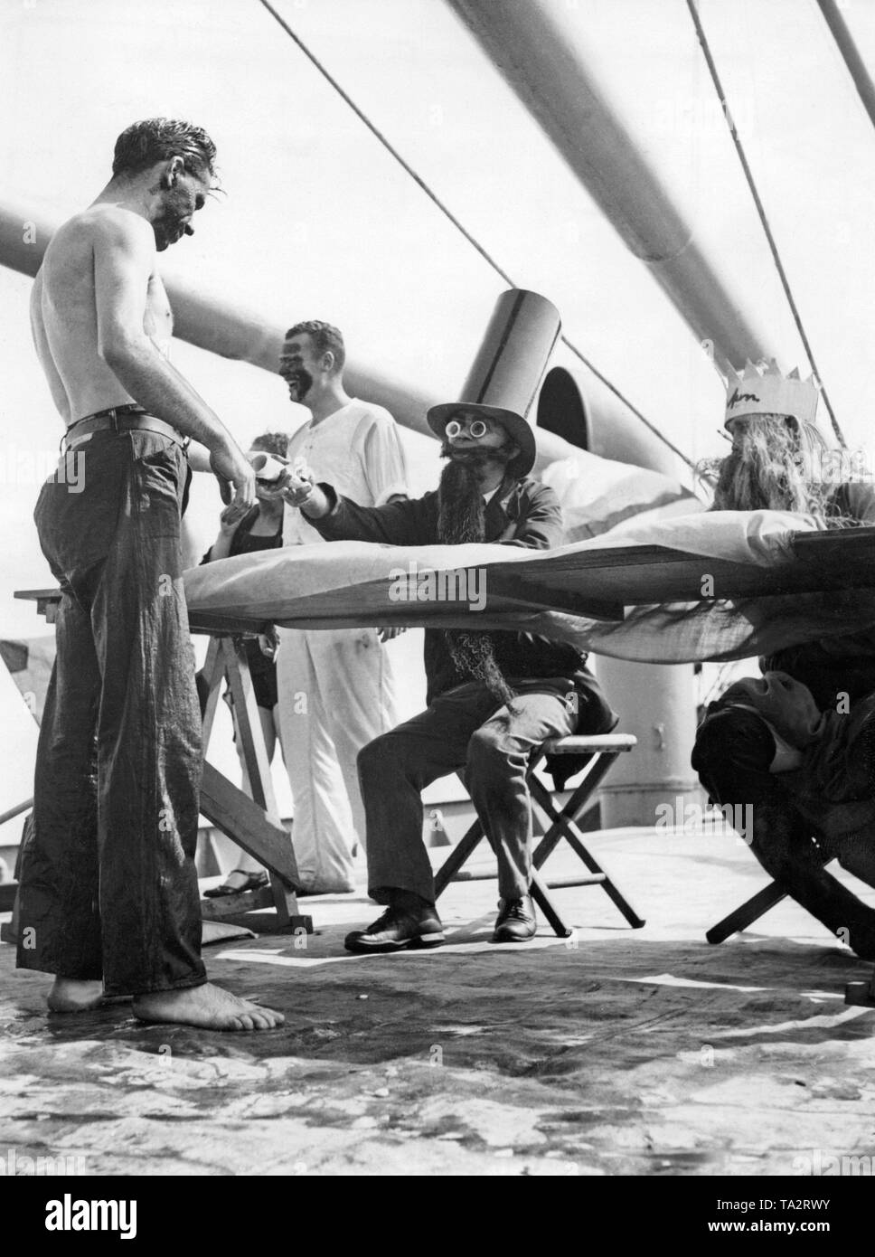 Seguendo la linea di attraversamento cerimonia, un marinaio riceve il suo certificato da due vecchi marinai, che mascherano come il dio del mare Nettuno e il suo segretario. Quando un marinaio attraversa l'Equatore per la prima volta, egli subisce una serie di rituali che termina nel battesimo equatoriale. Foto Stock