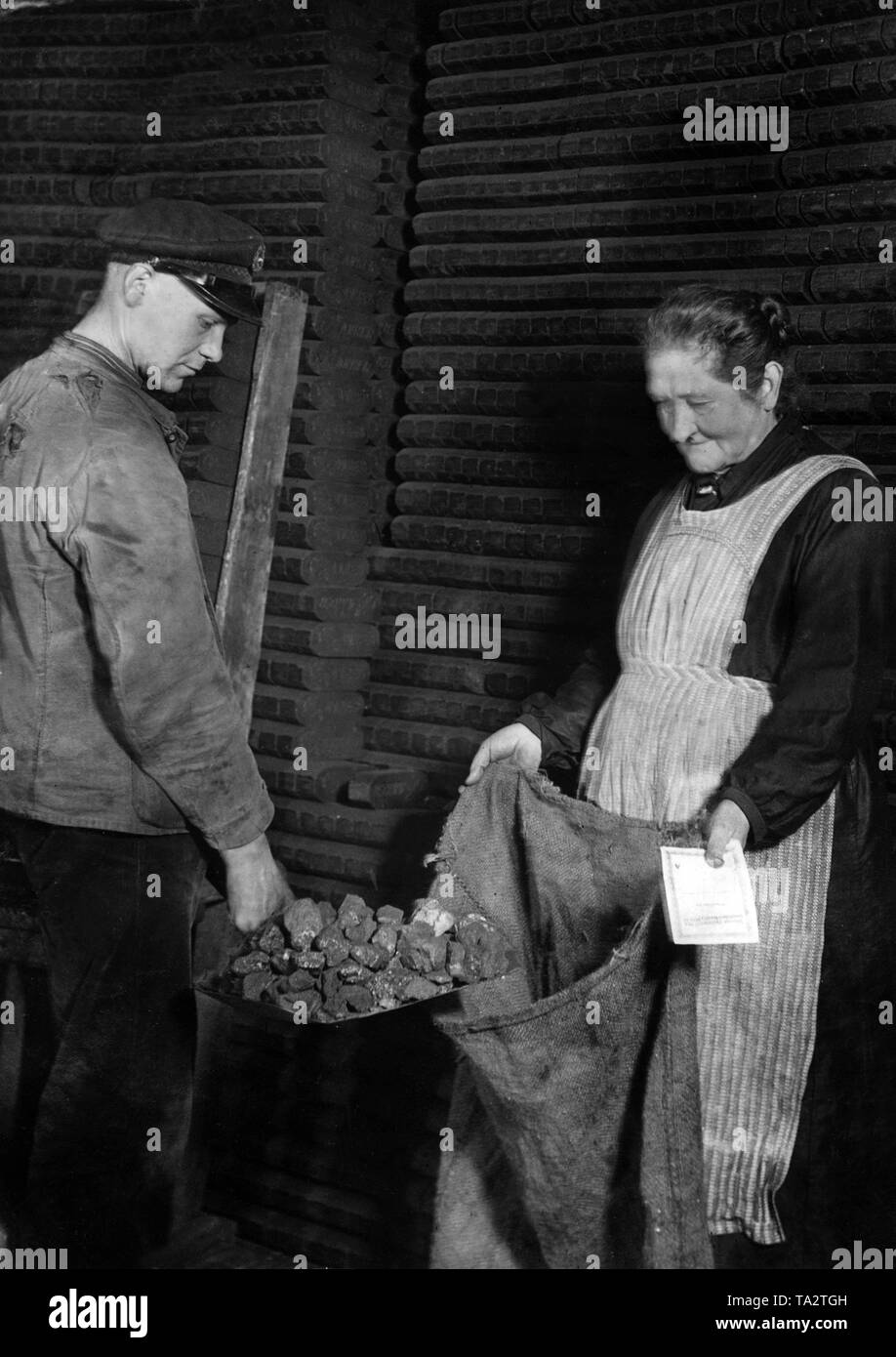 Una donna riceve i carboni da un concessionario per un buono di NS-Winterhilfswerk. Foto Stock