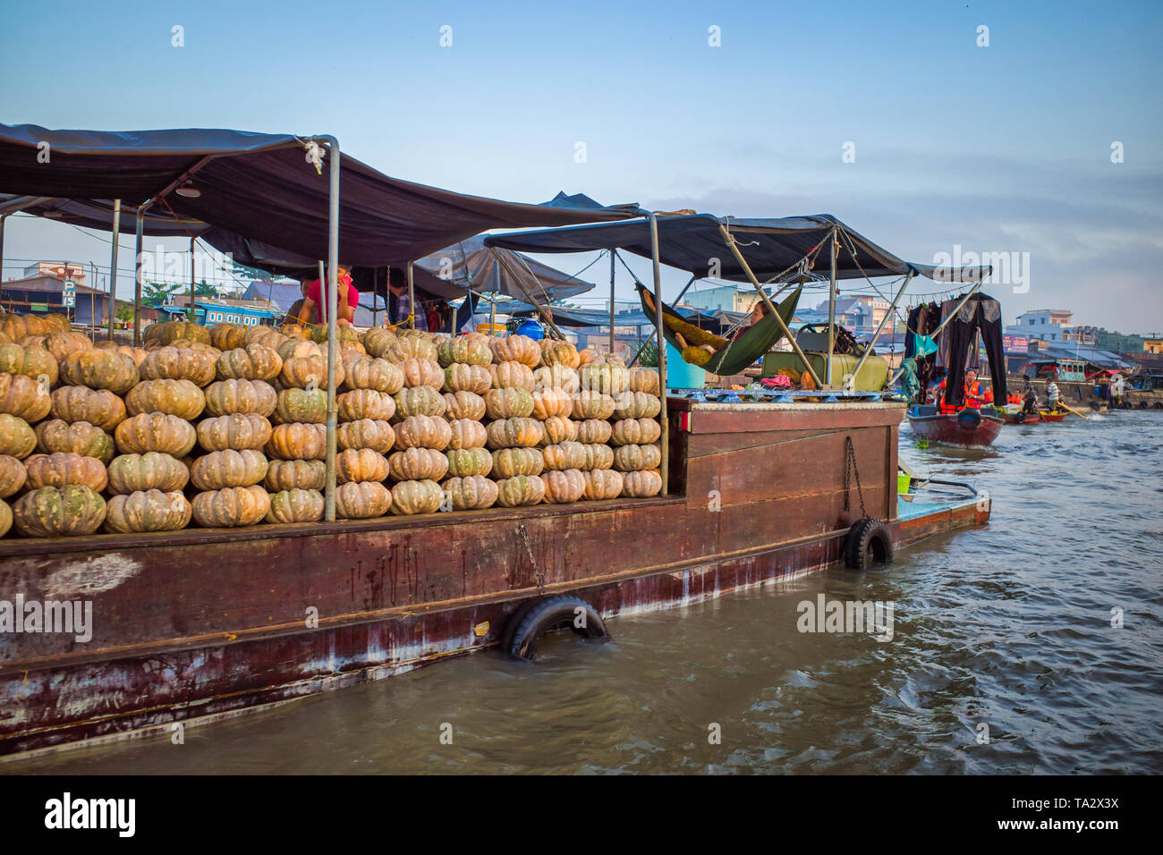 Can Tho, Vietnam - Marzo 28, 2019: mercato galleggiante nel delta del Mekong / trading barche all'alba. Zucche di grandi dimensioni su una chiatta. Una donna è a riposo in un loun Foto Stock