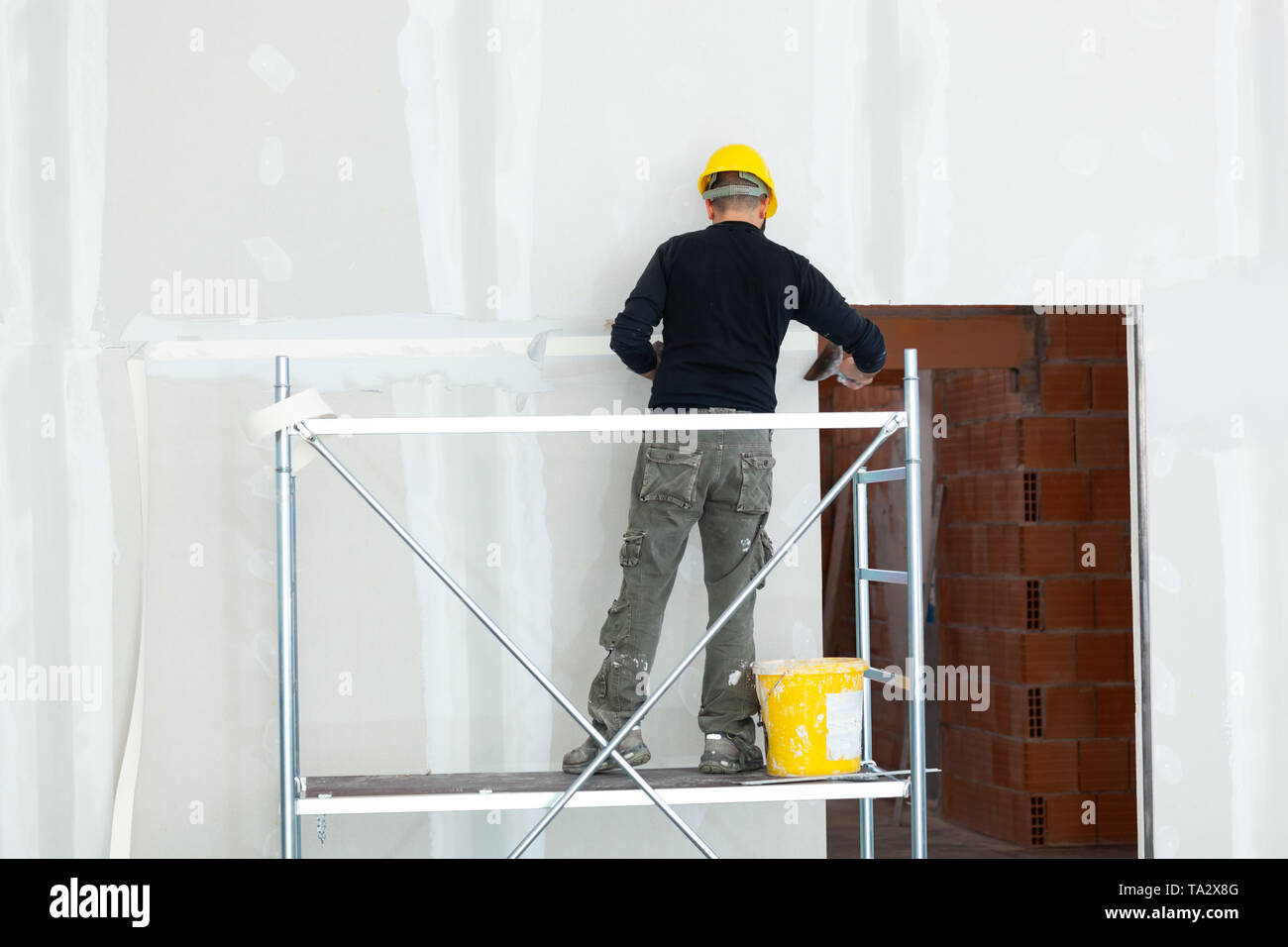 Allestimento interno, lavoratore intonacatura cartongesso parete. Foto Stock