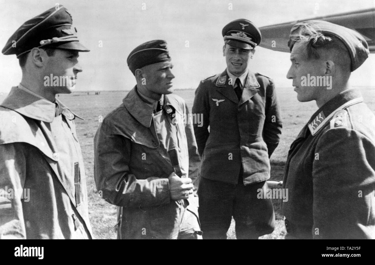 Un maestro artigiano della Luftwaffe (estrema destra) riporta al suo comandante dello squadrone (probabilmente sulla sinistra) la predisposizione di massa del motore in background. Foto: corrispondente di guerra Carstensen. Foto Stock