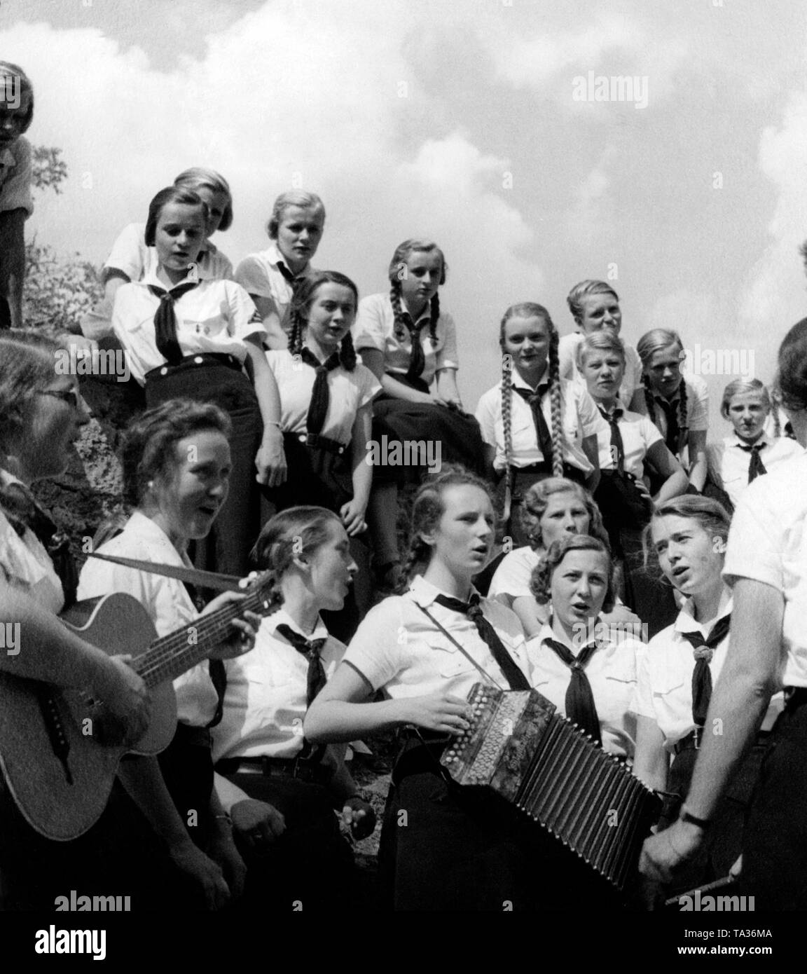 BDM-Fuehrerinnen, che frequentano una scuola di formazione del BDM a Neuchâtel Castello, cantare e suonare musica in un fossato. Foto Stock