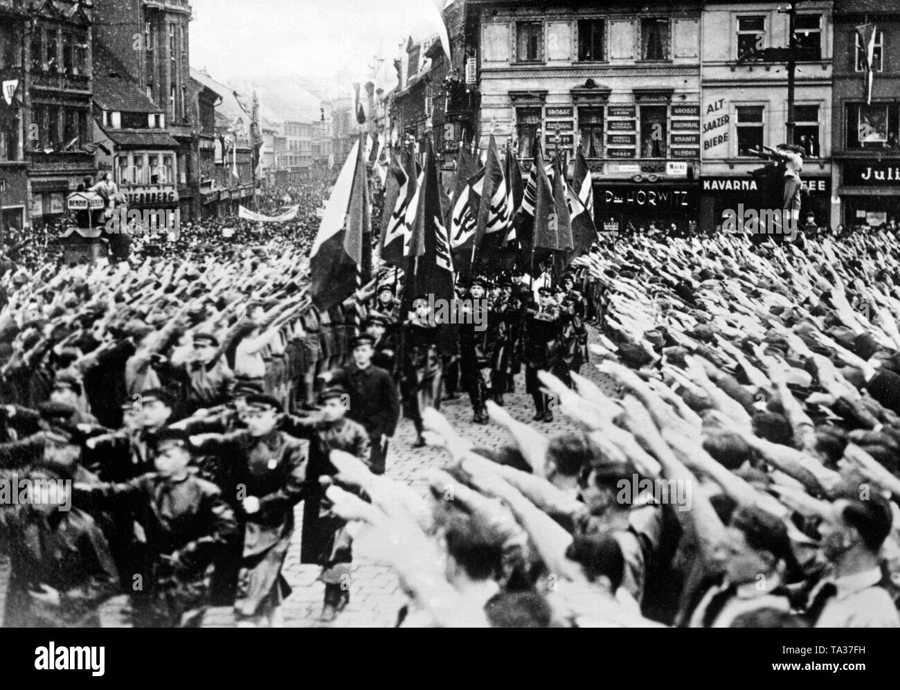 Le celebrazioni del 1 maggio in Teplitz-Schoenau (oggi Teplice). I membri del partito dei Sudeti tedesco, partito marzo attraverso la città. Spettatori eseguire il saluto di Hitler. Foto Stock