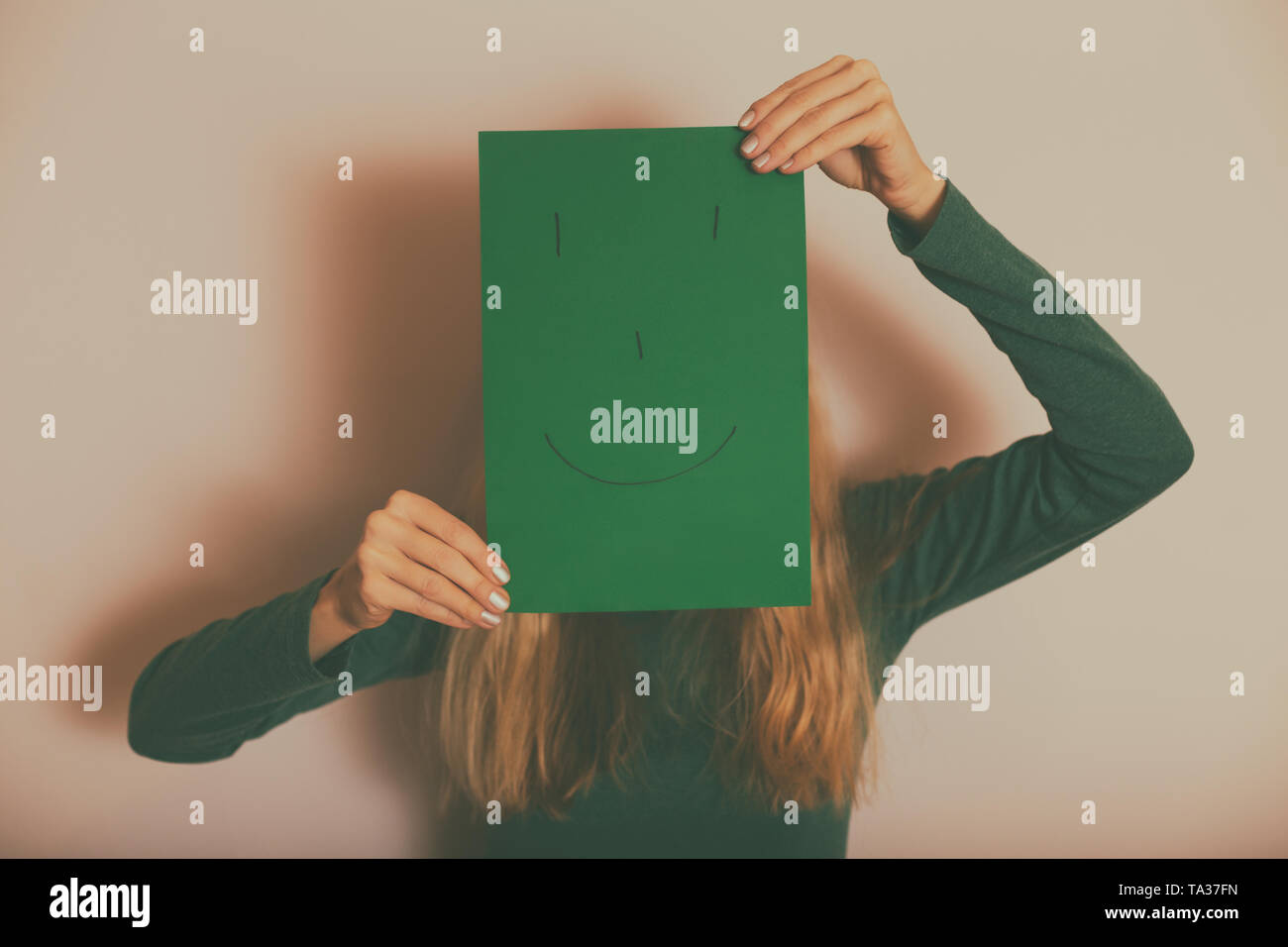 Donna con la faccia felice su carta in piedi nella parte anteriore della parete.tonica immagine. Foto Stock