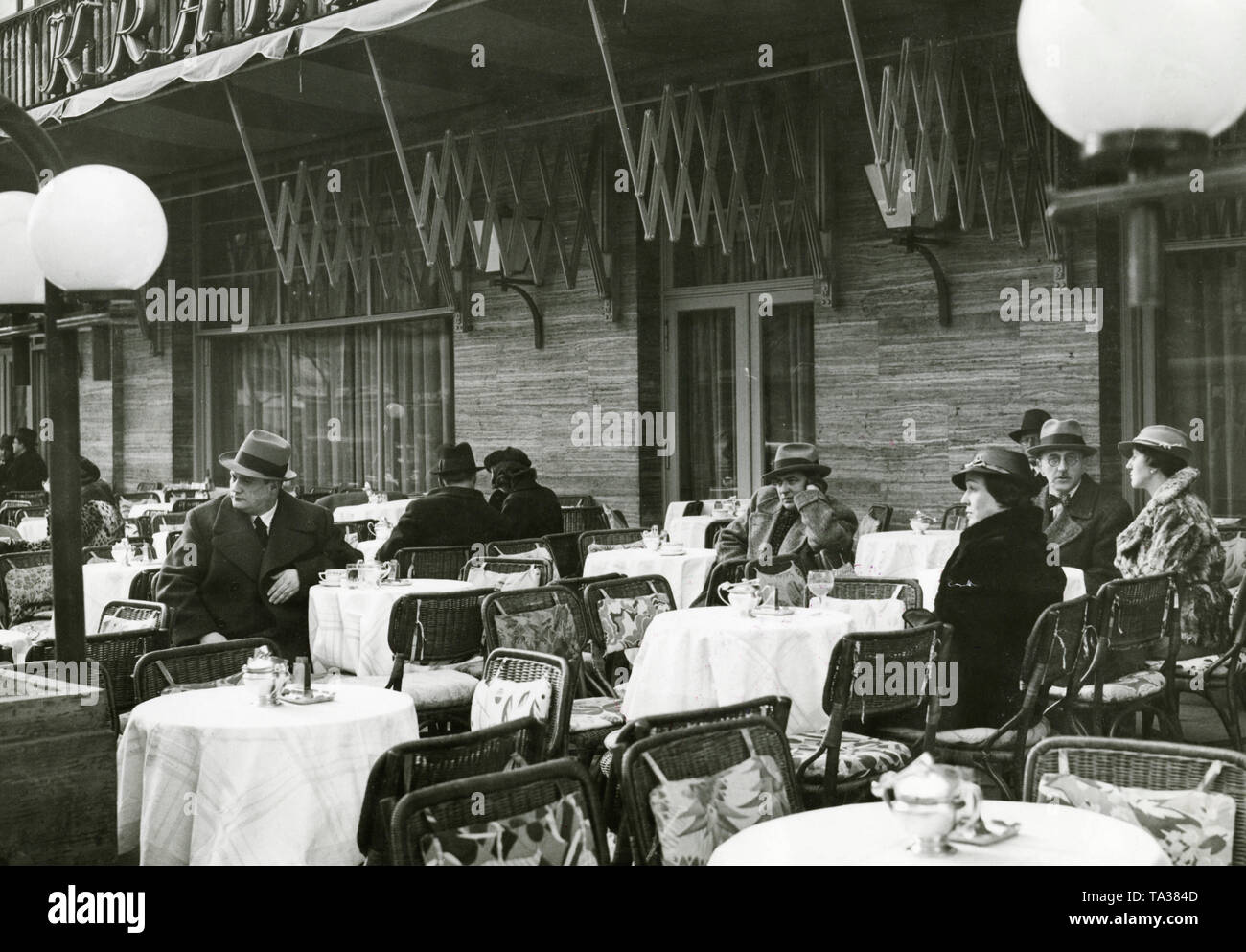 Alcuni ospiti sulla terrazza sulla strada del Cafe Kranzler a Berlino. Il primo Café Kranzler a Berlino è stato aperto nel 1825 da Johann Georg Kranzler come una piccola pasticceria in strada "Unter den Linden" nel distretto Mitte di Berlino. Nel 1932 aprì il secondo ramo dell'ex Café des Westens sotto il nome di 'Restaurant und Konditorei Kranzler' in la Joachimstaler Strasse (oggi Joachimsthaler Strasse) nel quartiere Charlottenburg. Entrambi gli edifici sono stati distrutti durante i raid aerei negli anni 1944 e 1945. Foto Stock