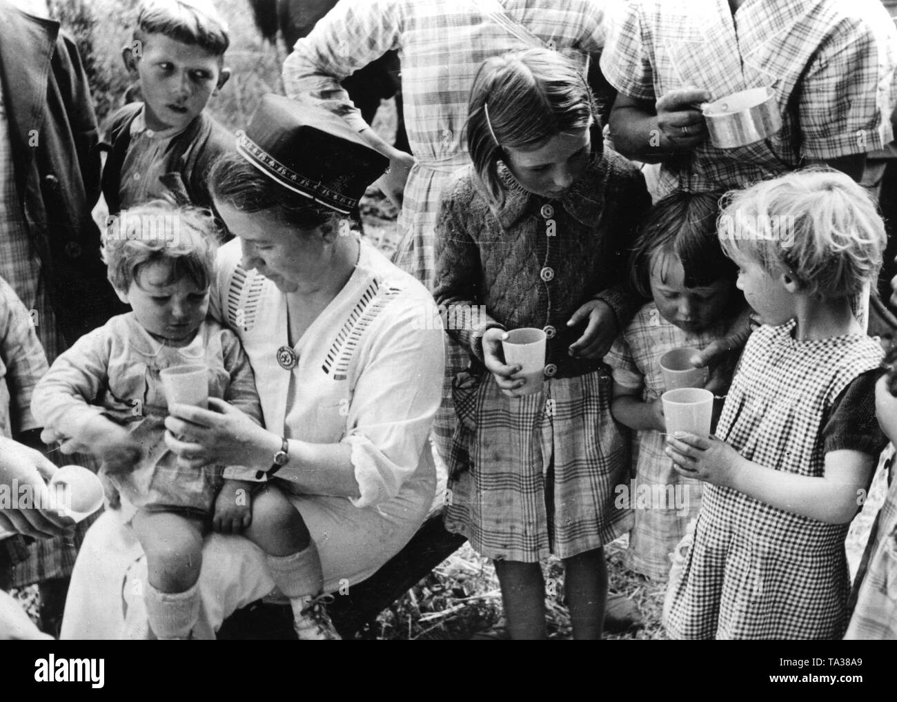 Gli infermieri del NS Volkswohlfahrt dare il latte alle famiglie che erano in francese inumazione camps. Reporter di guerra: Weber. Foto Stock