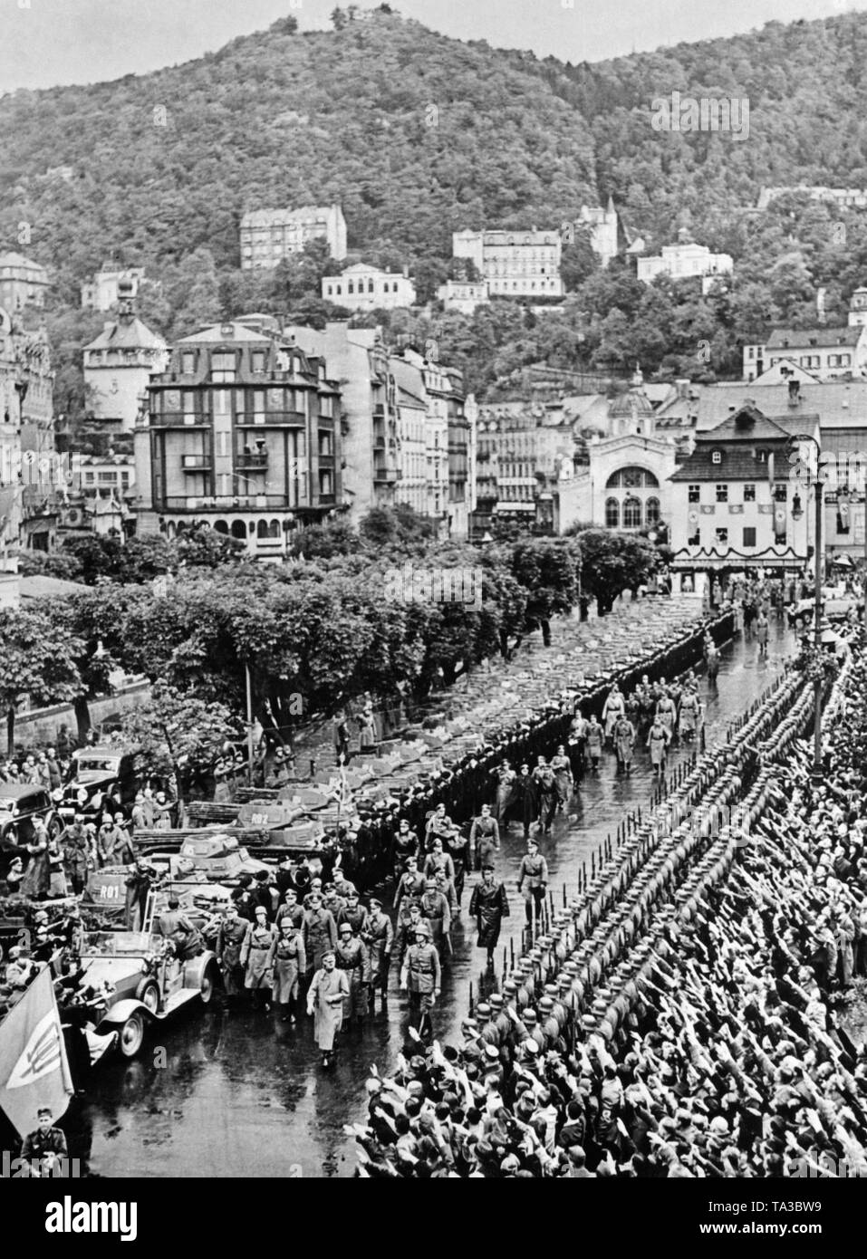 L'invasione delle truppe tedesche in Karlsbad (oggi Karlovy Vary). Alla testa della processione, Adolf Hitler. A sinistra lungo la strada sono serbatoi. Sulla destra, soldati e persone. Sulla sinistra una bandiera del SdP, i Sudeti partito tedesco. Foto Stock