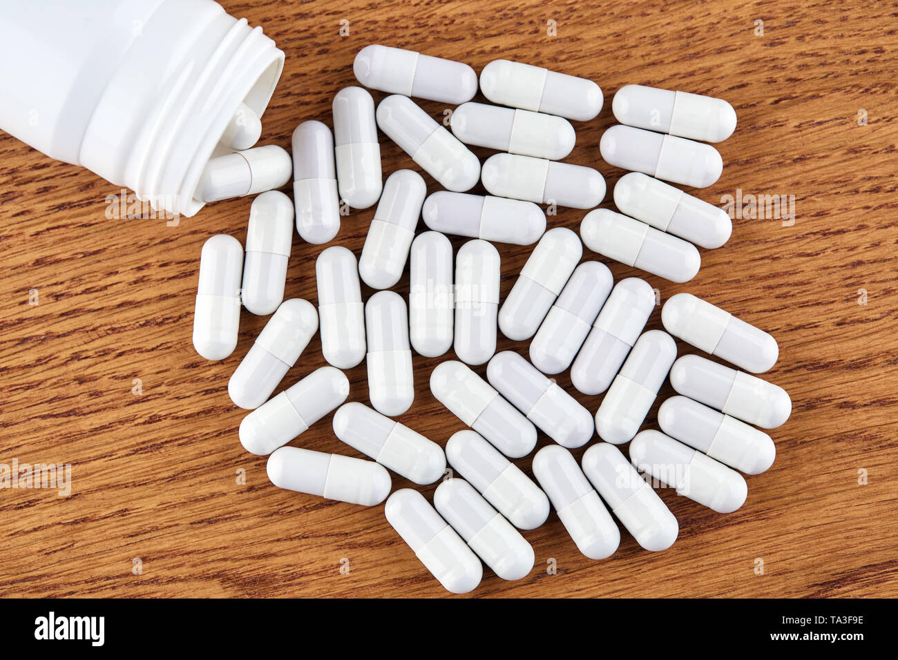 Molte pillole di bianco e la fiala di plastica su sfondo di legno. Foto Stock