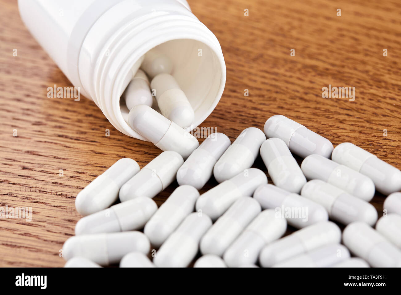 Molte pillole di bianco e la fiala di plastica su sfondo di legno. Foto Stock
