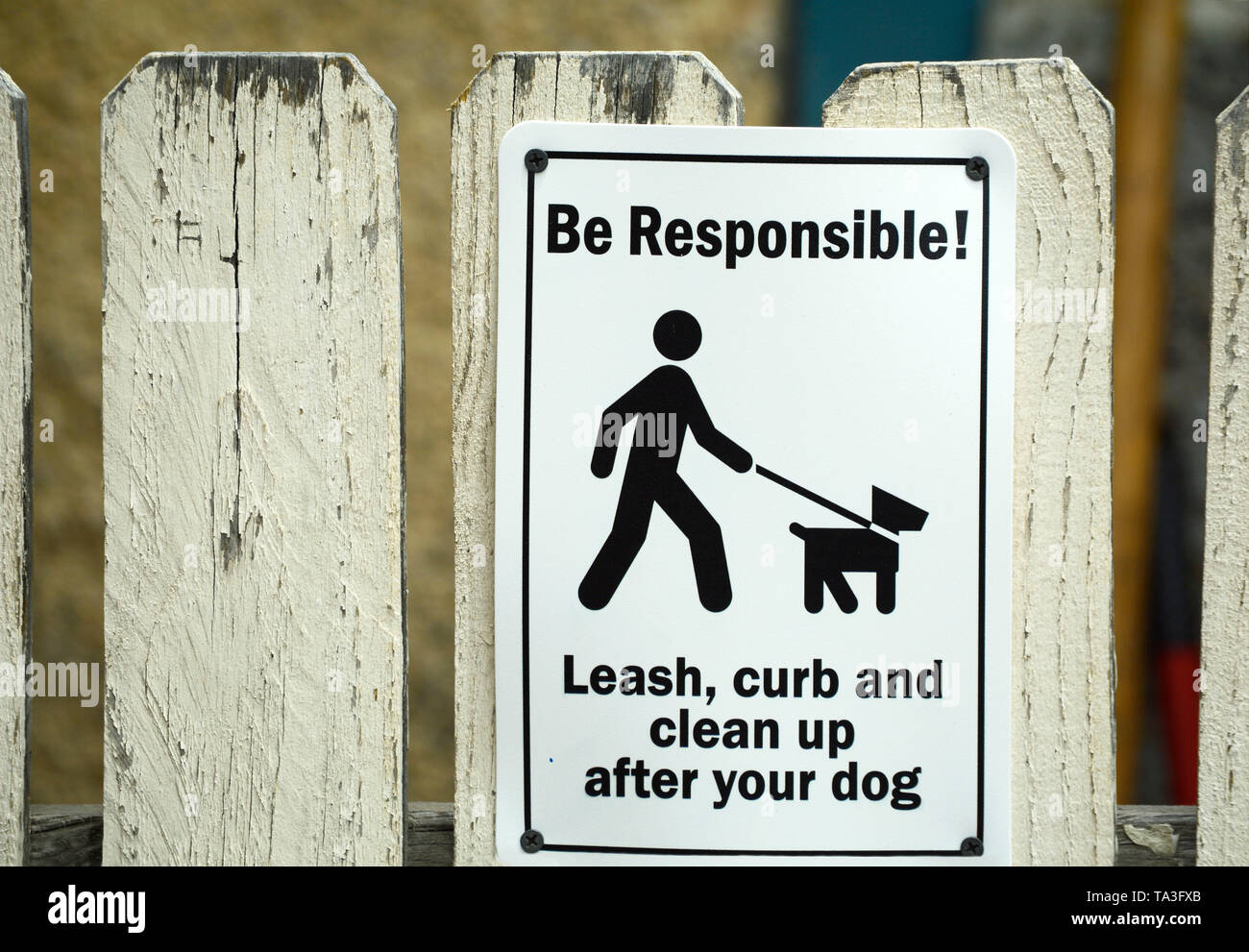 Un segno su un Picket Fence invita i possessori di animali al guinzaglio i loro cani e pulizia dopo i loro cani. Foto Stock