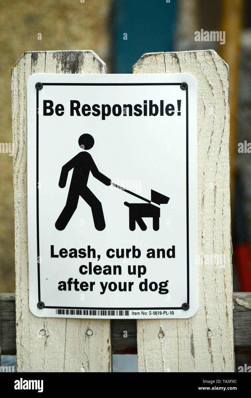 Un segno su un Picket Fence invita i possessori di animali al guinzaglio i loro cani e pulizia dopo i loro cani. Foto Stock