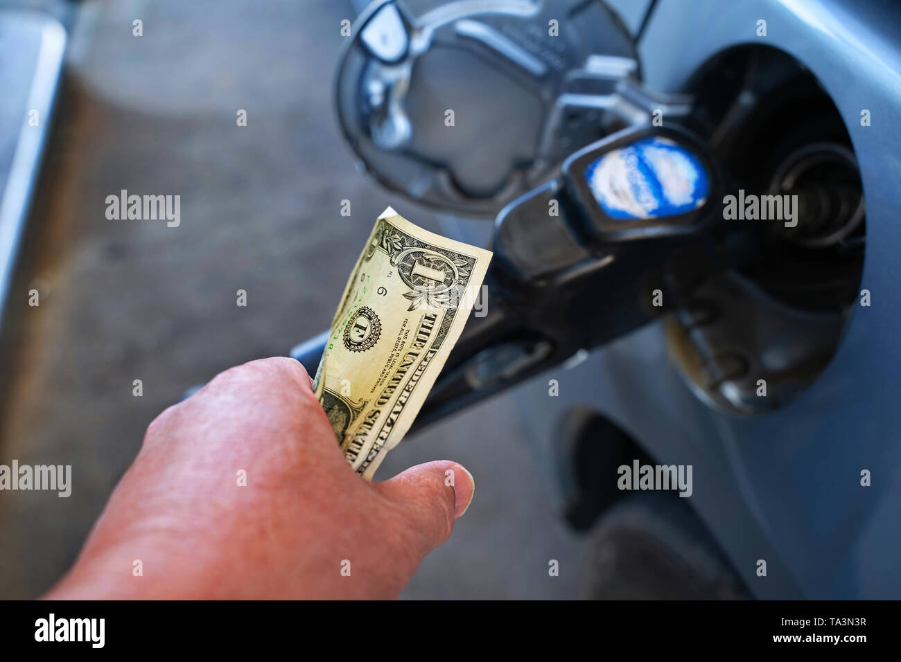 Mano bloccando saldamente su di un dollaro ponendo nel contempo gas nell'auto. Foto Stock