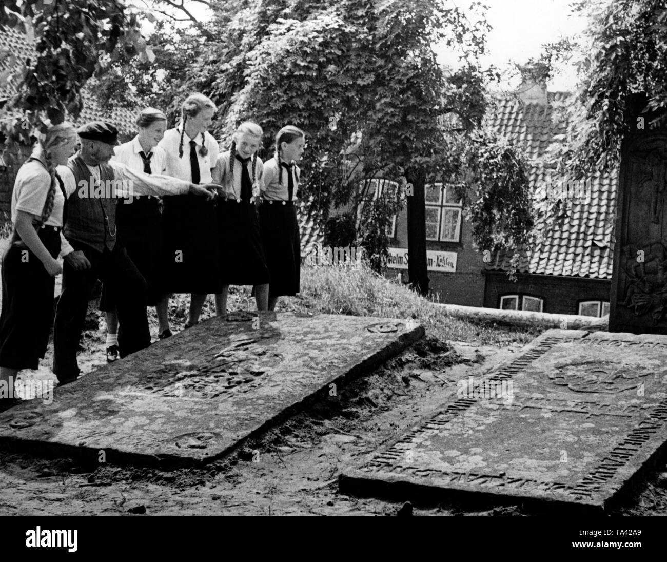 Un gruppo di ragazze BDM è visitare diverse tombe a Geschlechterfriedhof Lunden (cimitero Lunden) in Dithmarschen. Foto Stock