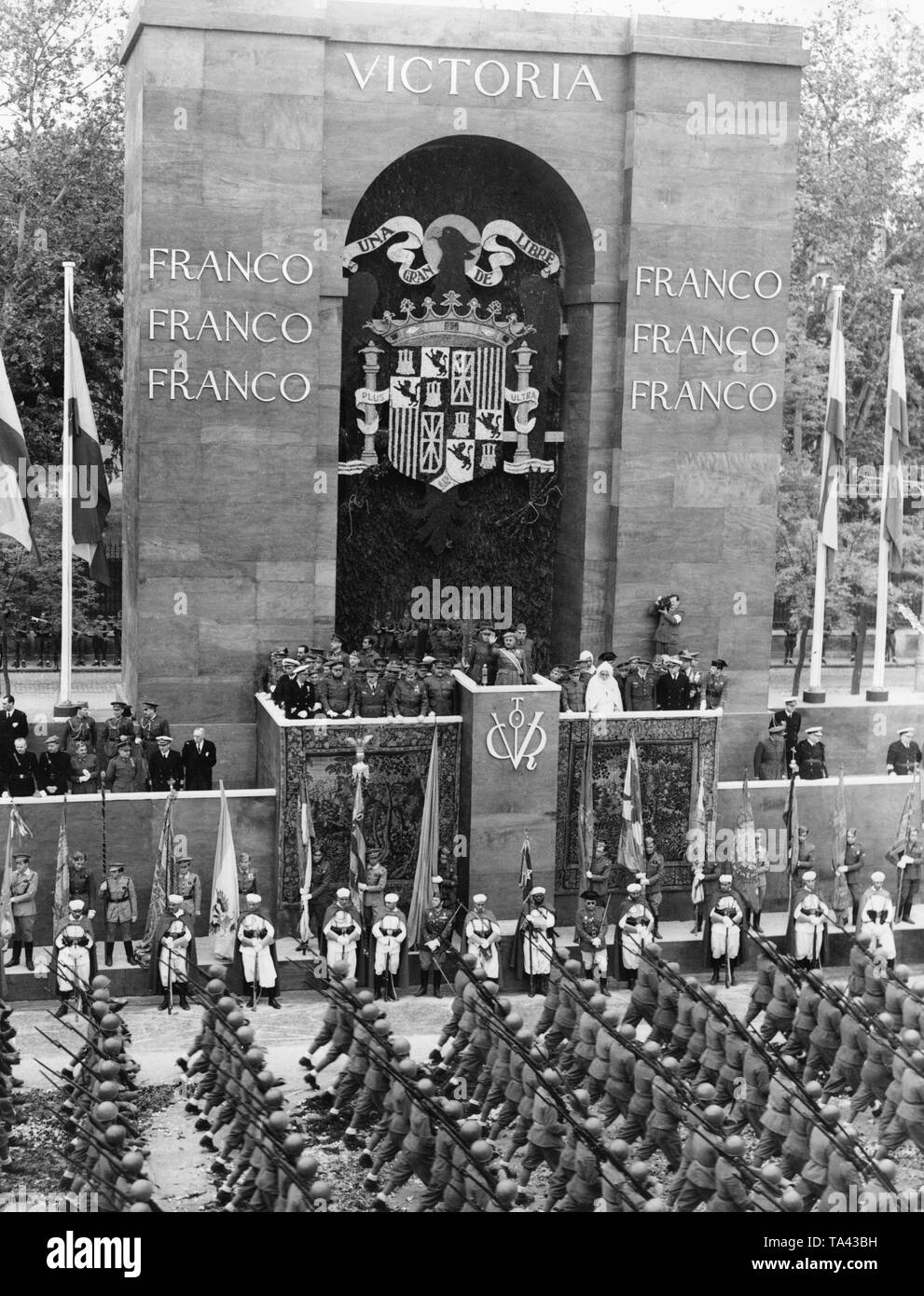 Foto del caudillo generale Francisco Franco della fase durante la Victory Parade nel Paseo della Castellana, Madrid, il 19 maggio 1939. Franco è salutato sulle tribune, circondata da alti ufficiali e dignitari. Un gruppo di soldati italiani dal volontario Corpo truppe volontarie è marciare dall'arco trionfale. Foto Stock