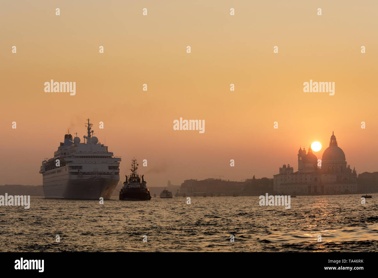 Un rimorchiatore di matasse di una nave da crociera in Bacino San Marco al tramonto a Venezia in Italia. Foto Stock