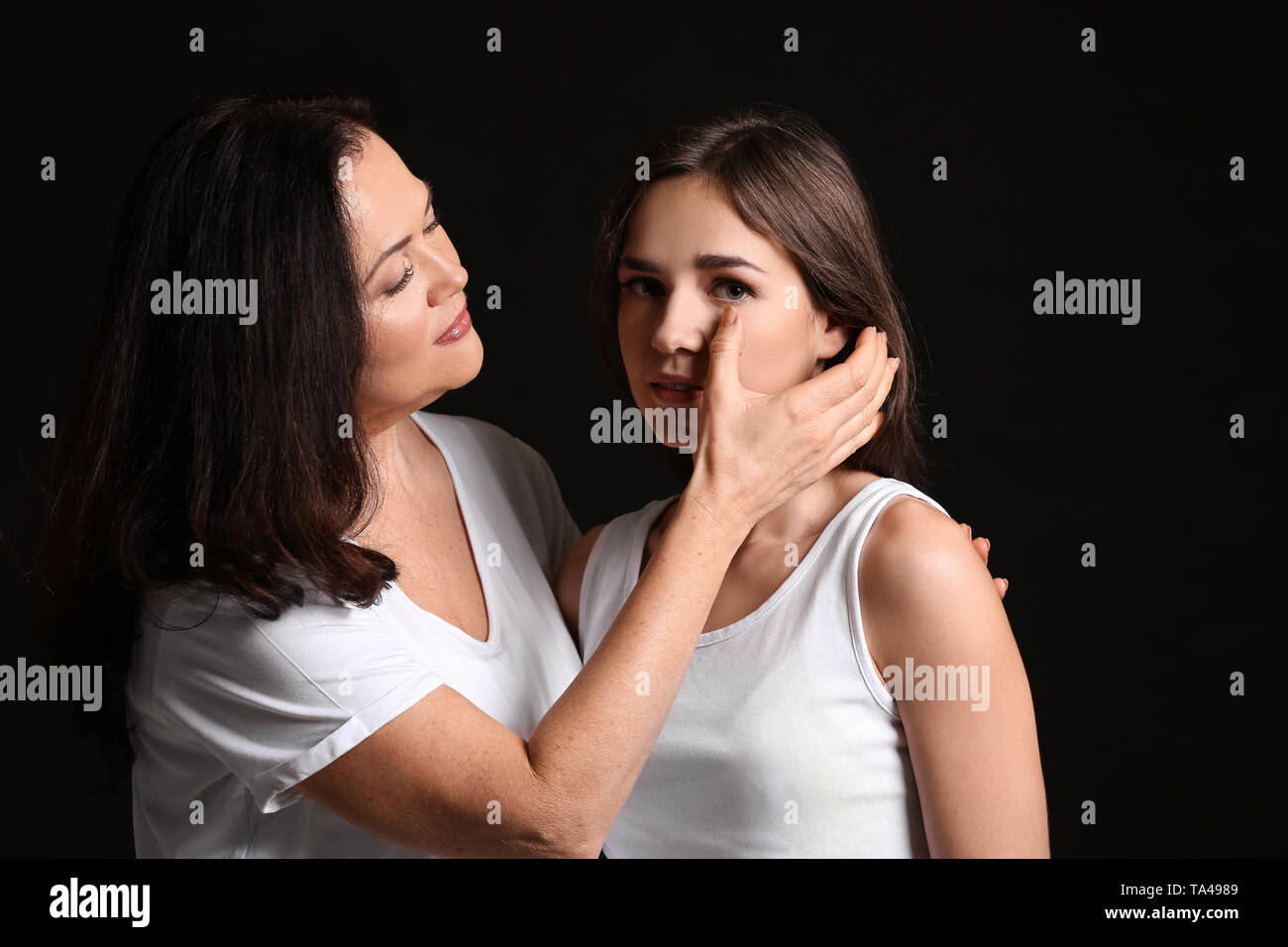 Donna calmare la figlia su sfondo scuro Foto Stock