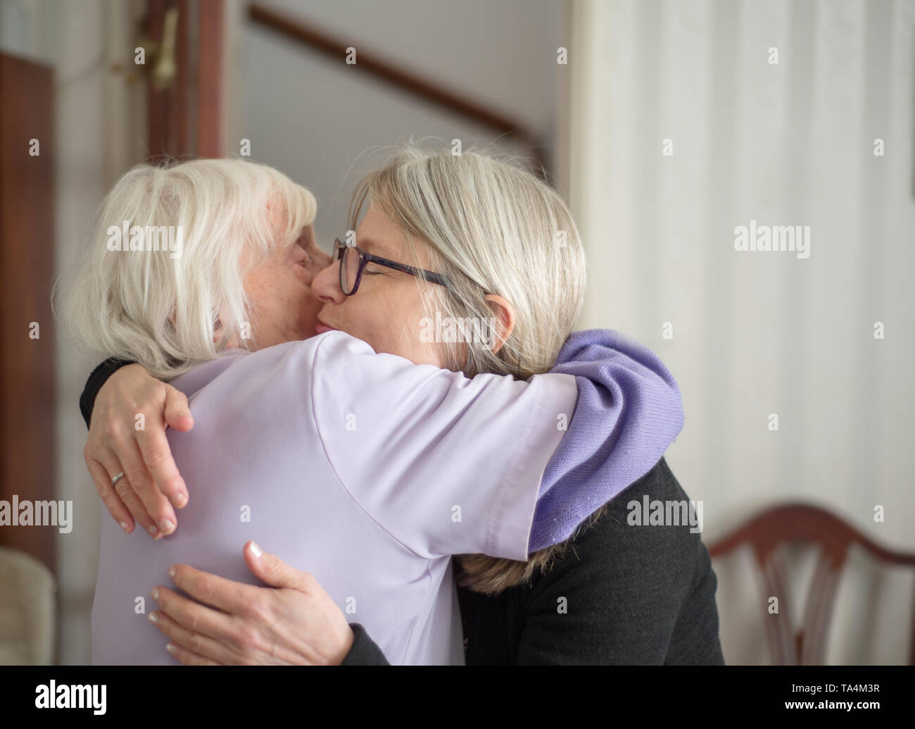 Dopo una visita per vedere la sua anziani e non vedenti madre,la figlia abbracci e dice addio a sua mamma, prima del suo lungo viaggio verso casa. Foto Stock