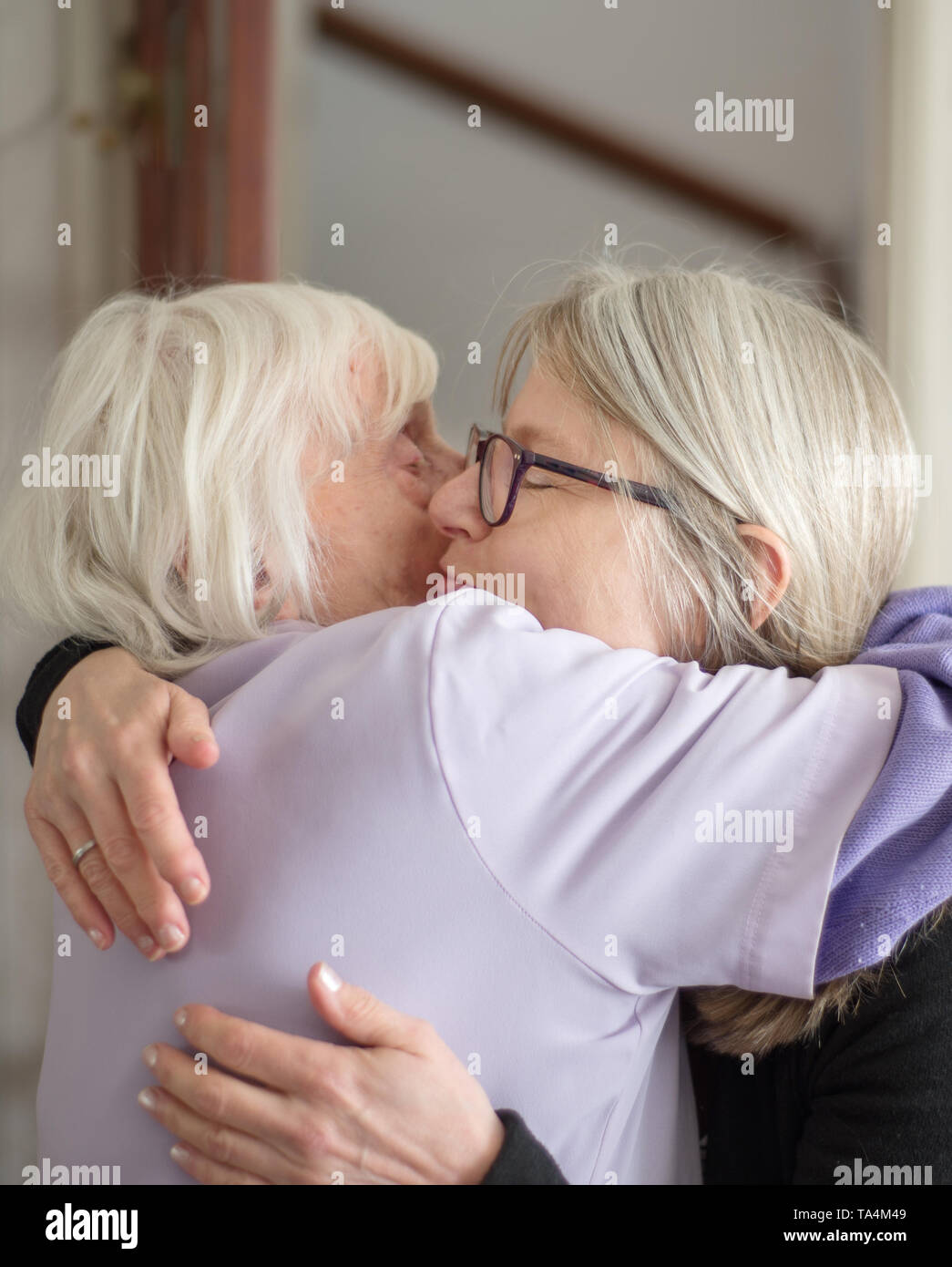 Dopo una visita per vedere la sua anziani e non vedenti madre,la figlia abbracci e dice addio a sua mamma, prima del suo lungo viaggio verso casa. Foto Stock