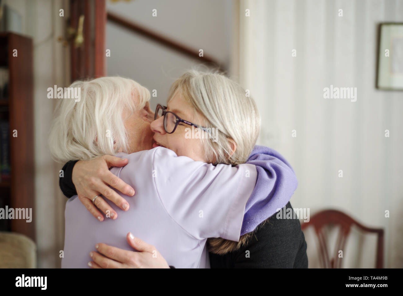 Un triste addio-dopo una visita per vedere la sua anziani e non vedenti madre,la figlia abbracci e dice addio a sua mamma, prima della sua trasmissione lungo back hom Foto Stock