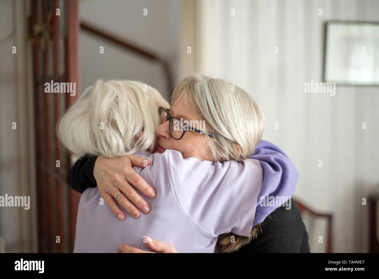 La madre non vuole che sua figlia a lasciare dopo una visita per vedere la sua anziani e non vedenti madre,la figlia abbracci e dice addio a sua mamma, b Foto Stock