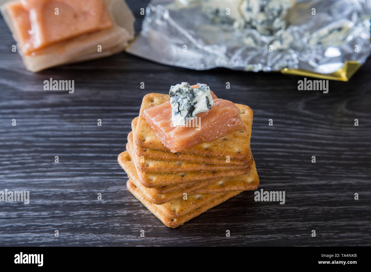 Deliziosa casa pasta di mela cotogna servita con crema vena blu formaggio e cracker di frumento. Su sfondo scuro, bel contrasto. Combinazione ideale. Foto Stock