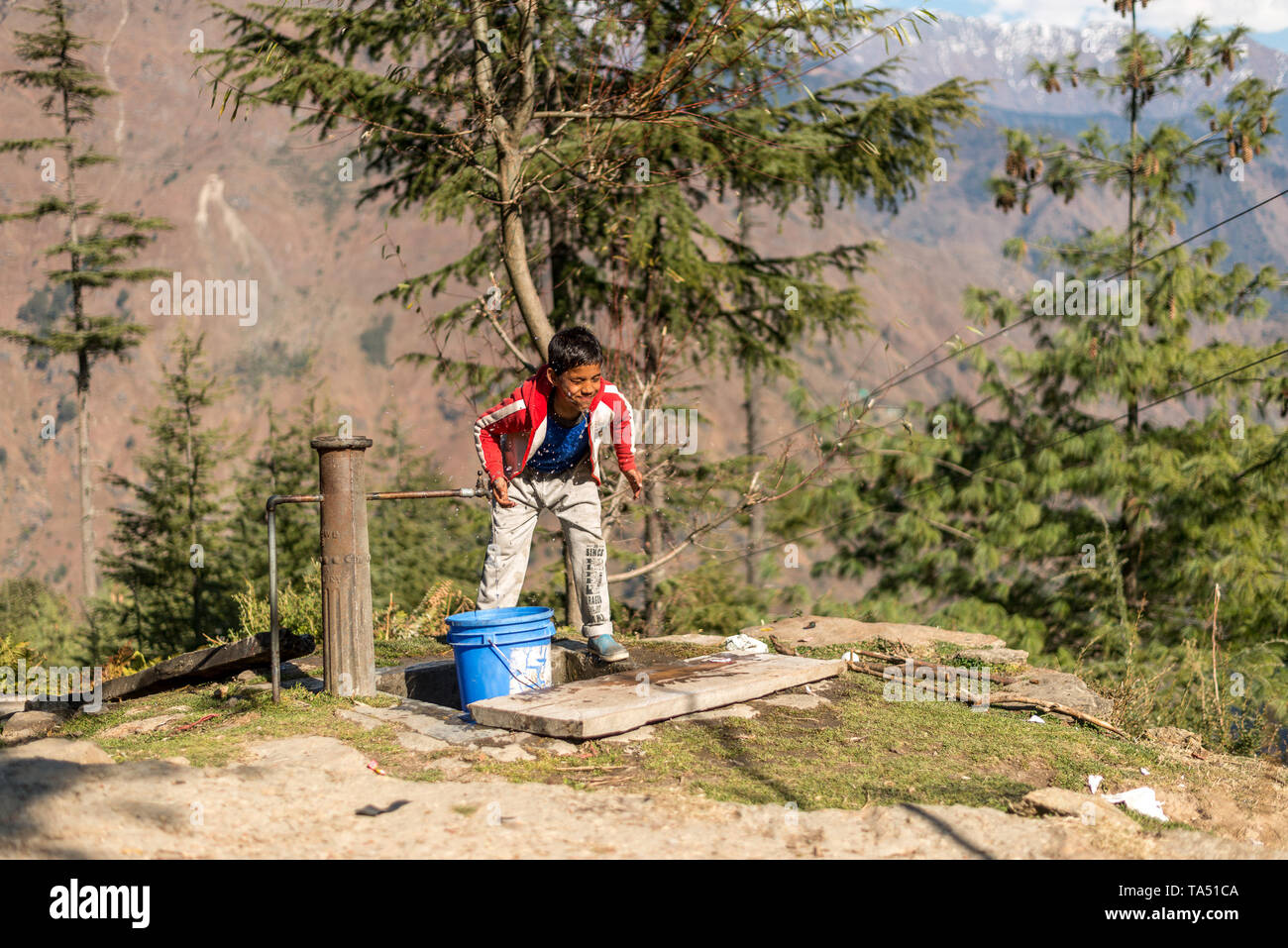 Kullu, Himachal Pradesh, India - 09 Dicembre 2018 : Un ragazzo il lavaggio la sua faccia da acqua di rubinetto in montagna Foto Stock