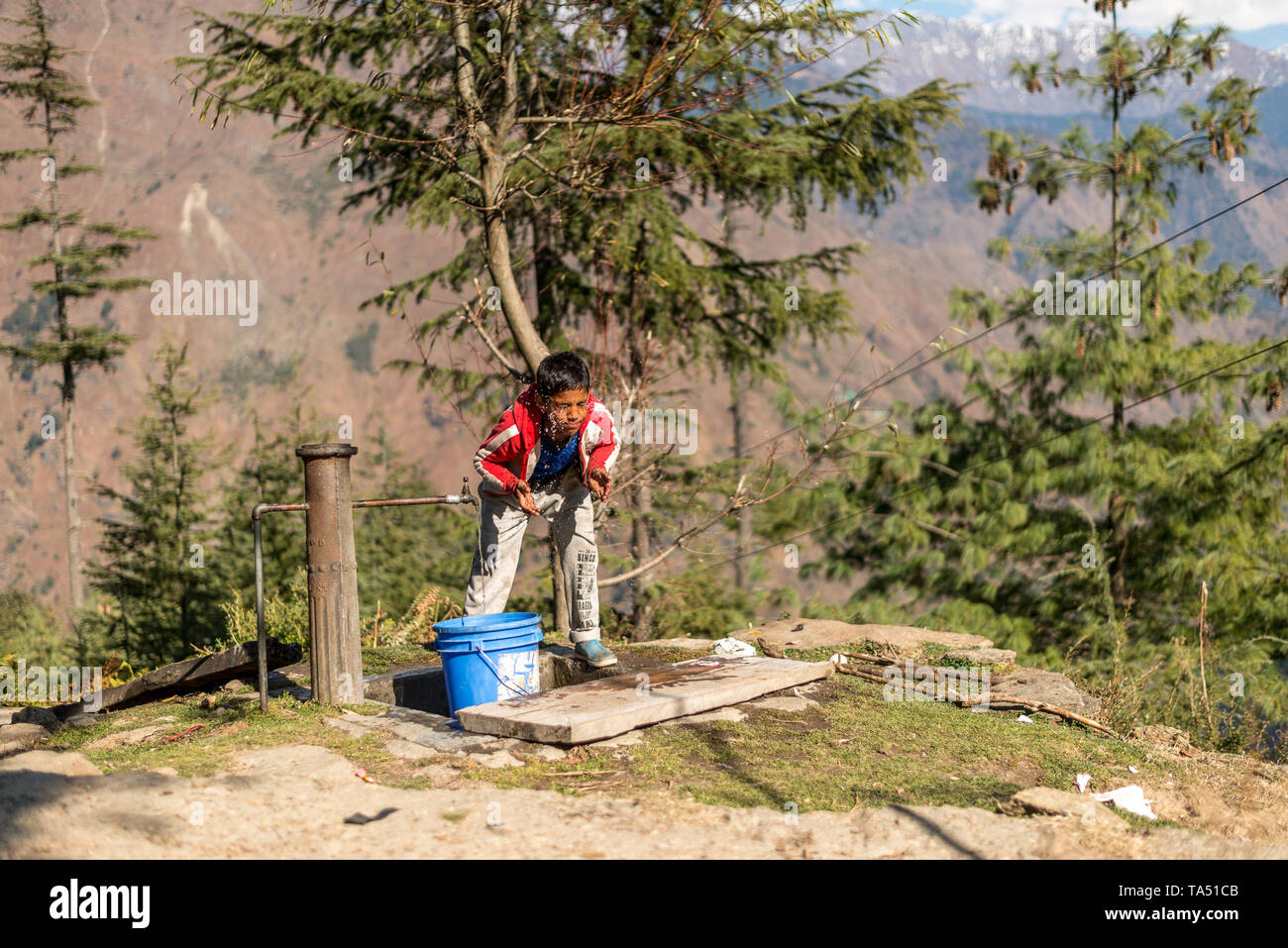 Kullu, Himachal Pradesh, India - 09 Dicembre 2018 : Un ragazzo il lavaggio la sua faccia da acqua di rubinetto in montagna Foto Stock