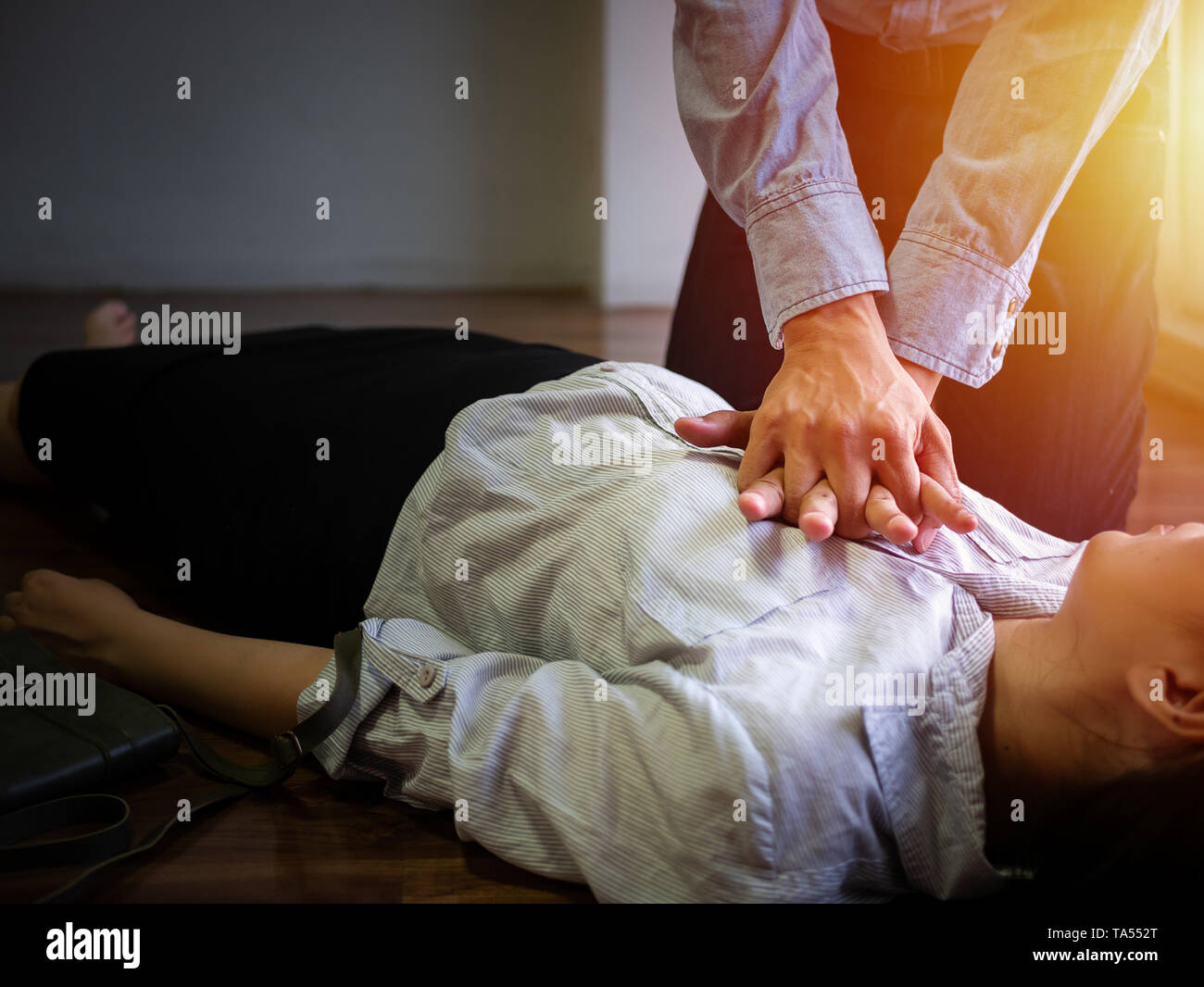 Ufficio Volontariato uomo utilizzare la pompa a mano sul petto per il primo soccorso RCP di emergenza su attacco di cuore donna inconscio, tentare di rianimazione del paziente donna al lavoro Foto Stock