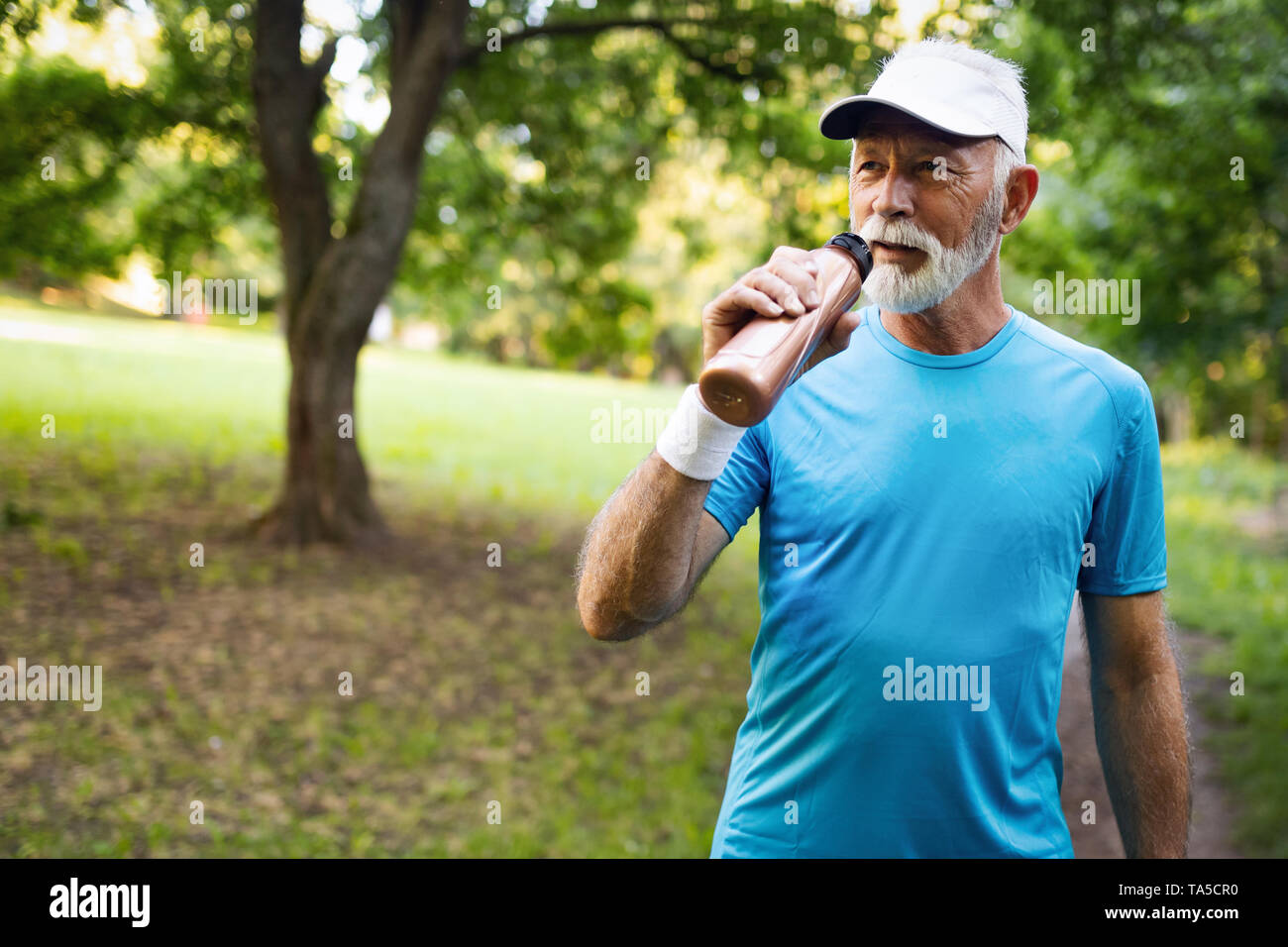 Bel uomo senior riposo dopo fare jogging al parco in una giornata di sole. Foto Stock